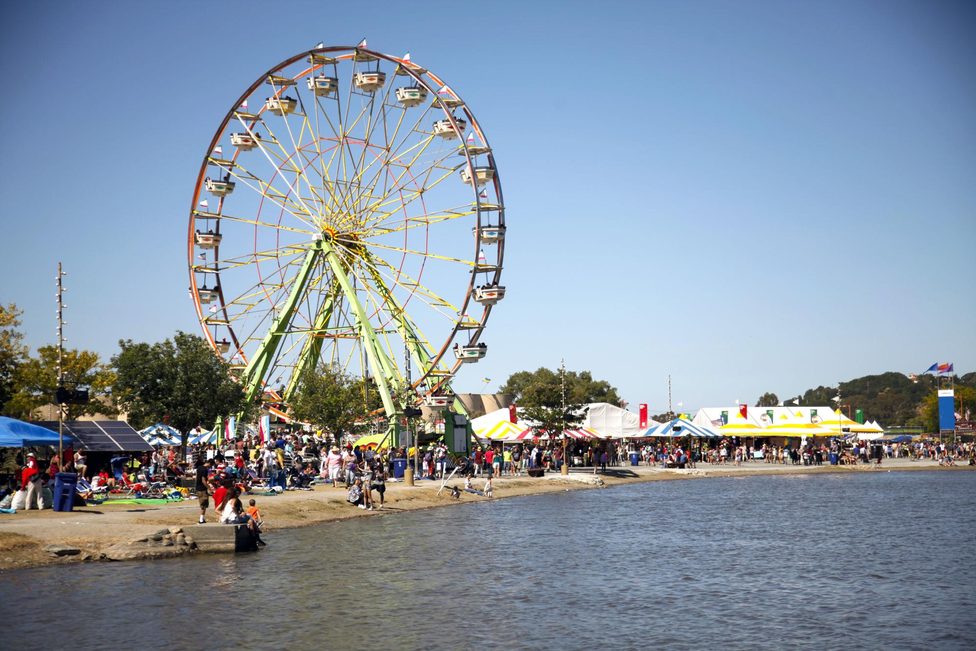 Ferriswheel at the Marin County fairgrounds next to the Lagoon with people on the beach.