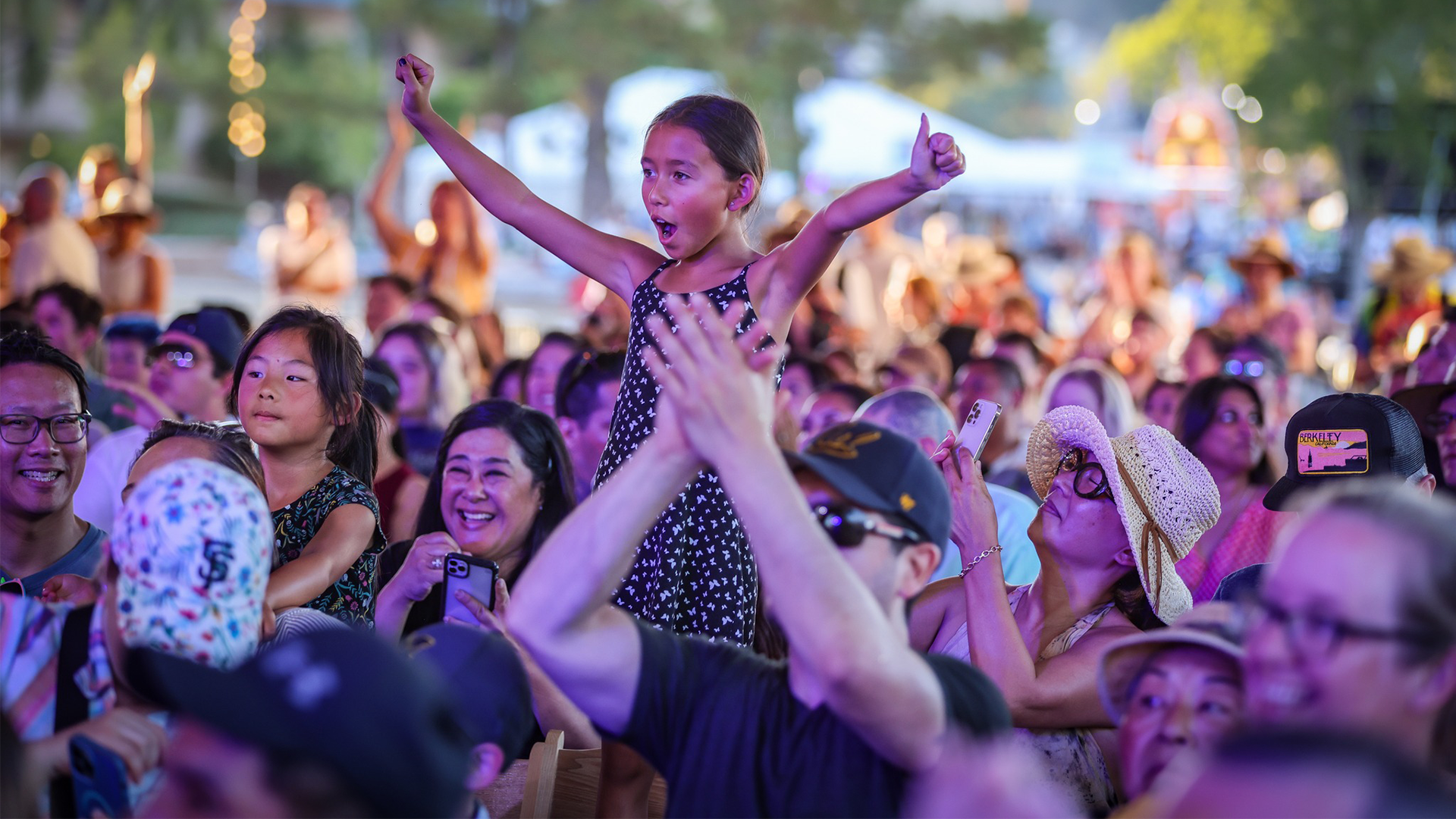 A adolescent girl stands and cheers at an outdoor concert at the Marin Center.