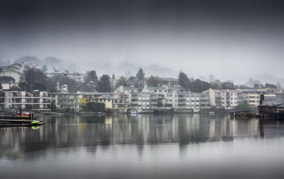 A landscape photograph of a foggy neighborhood on the water.