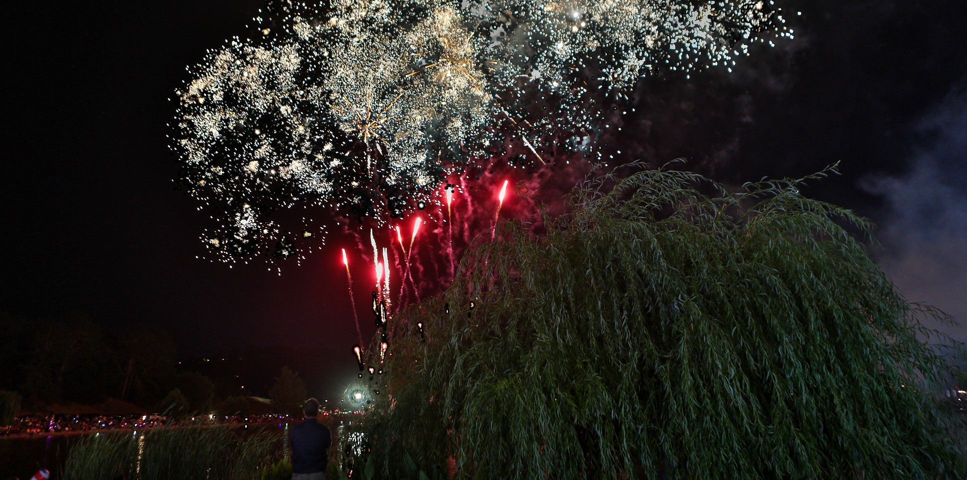 A view of County Fair fireworks booming over the lagoon at night.