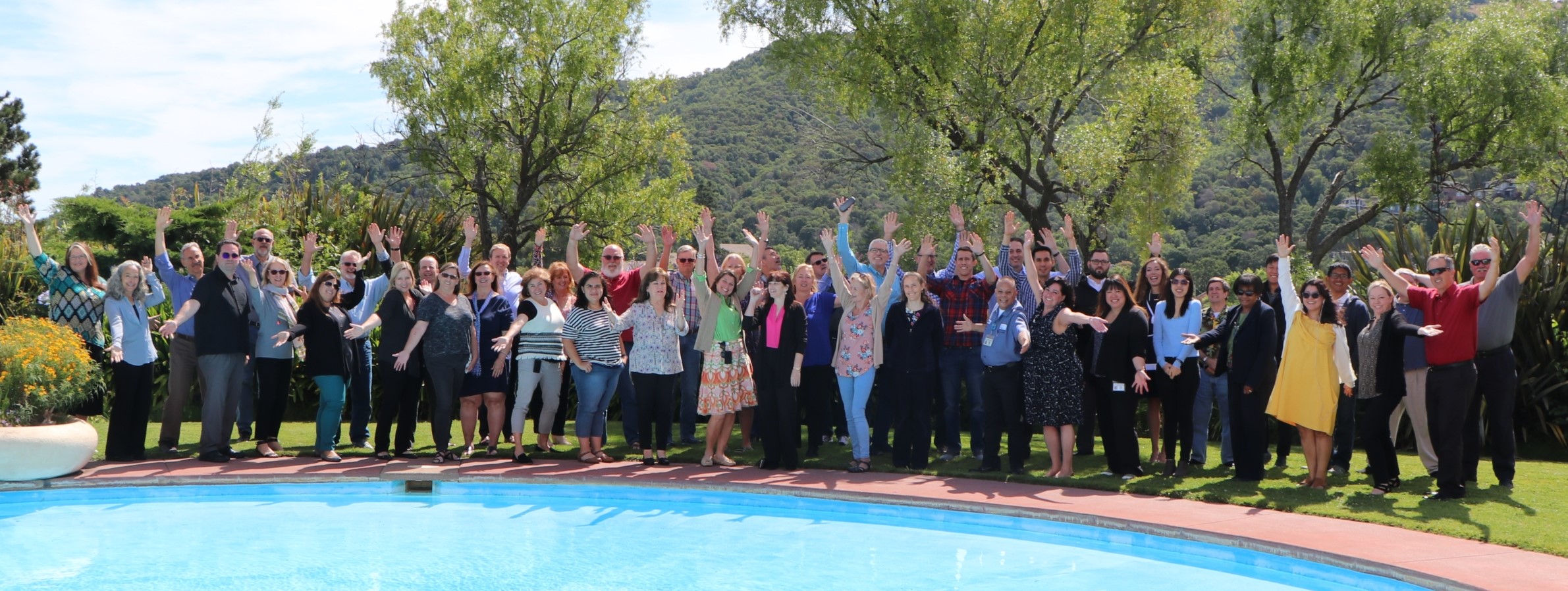 Several dozen employees of the Assessor Recorder County Clerk staff pose near a pond.