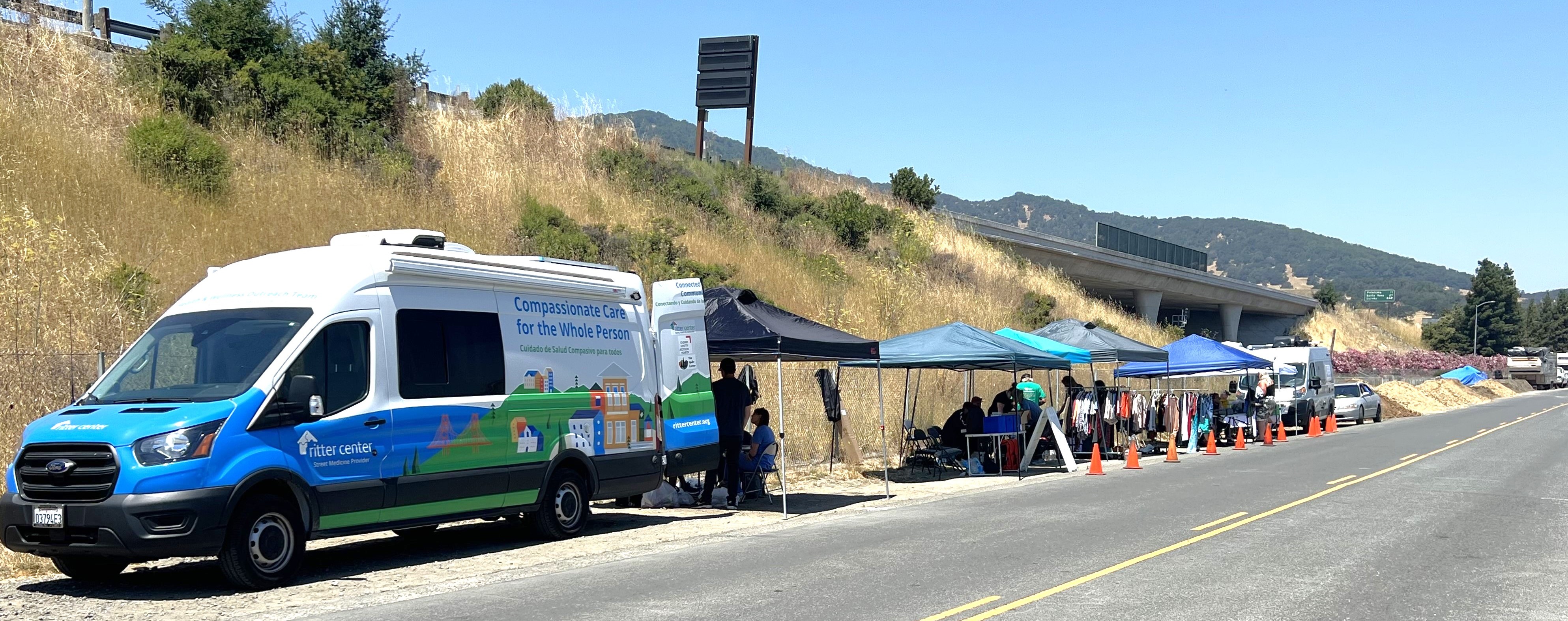 A view of Binford Road shows a van with supportive services open to assist residents as well as tents set up with resources.