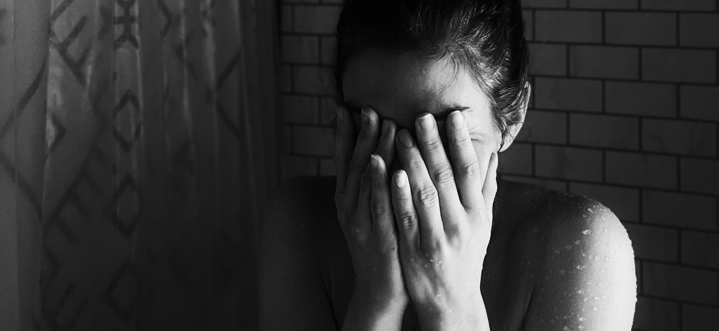 A distraught woman holds her hands in front of her face.