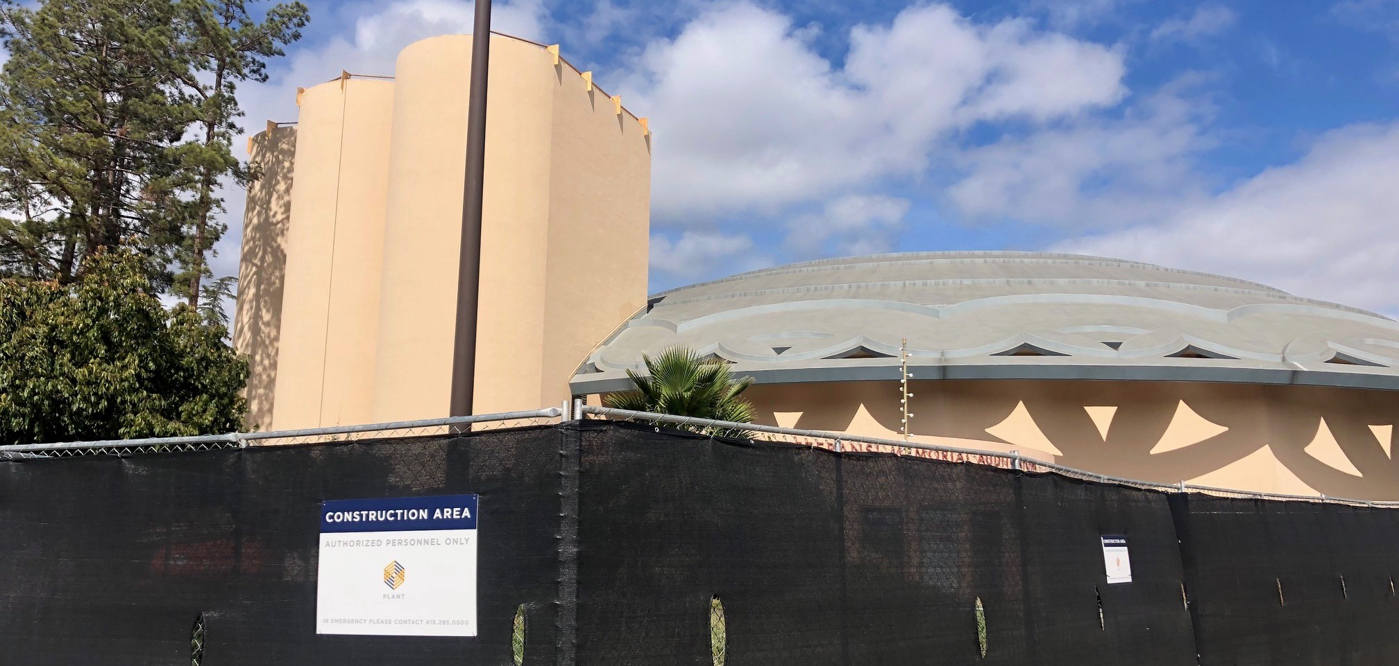 An exterior view of Veterans' Memorial Auditorium showing fencing and mesh prevention people from entering the construction zone.