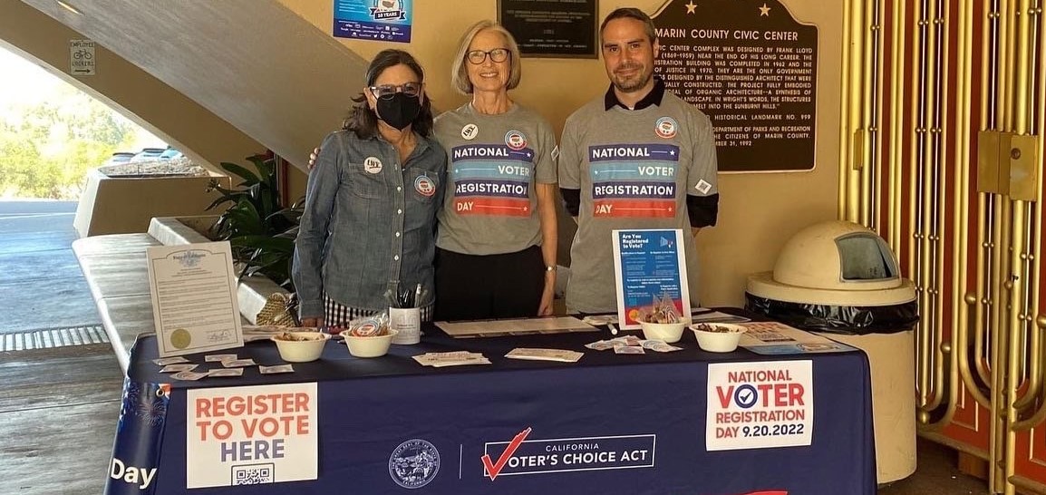 Three people pose at the National Voter Registration Day table outside the Civic Center. 