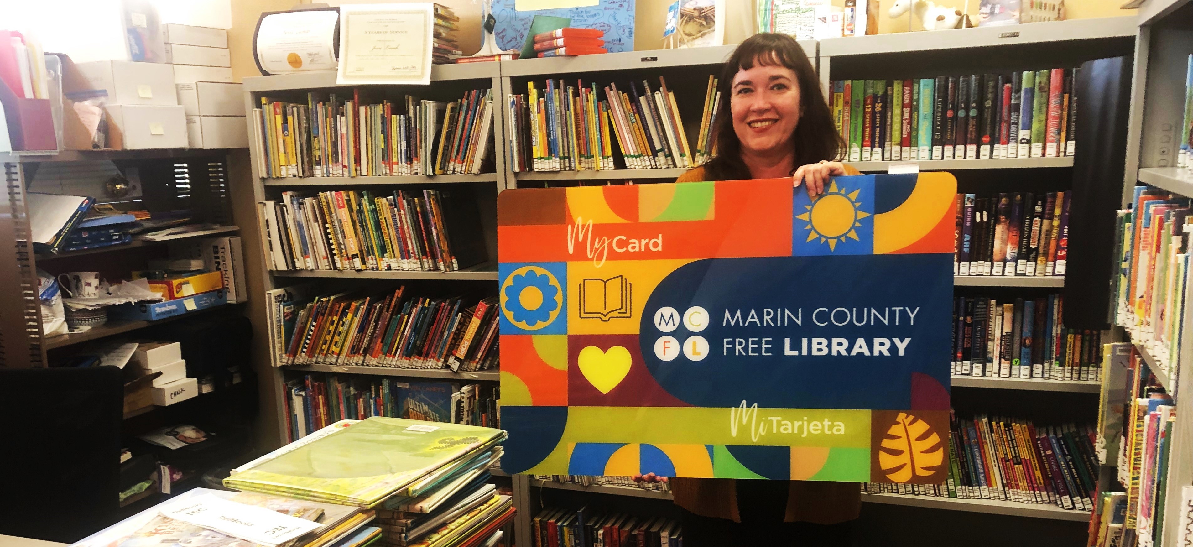Library Director Lana Adlawan holds up an oversized Student My Card sign.