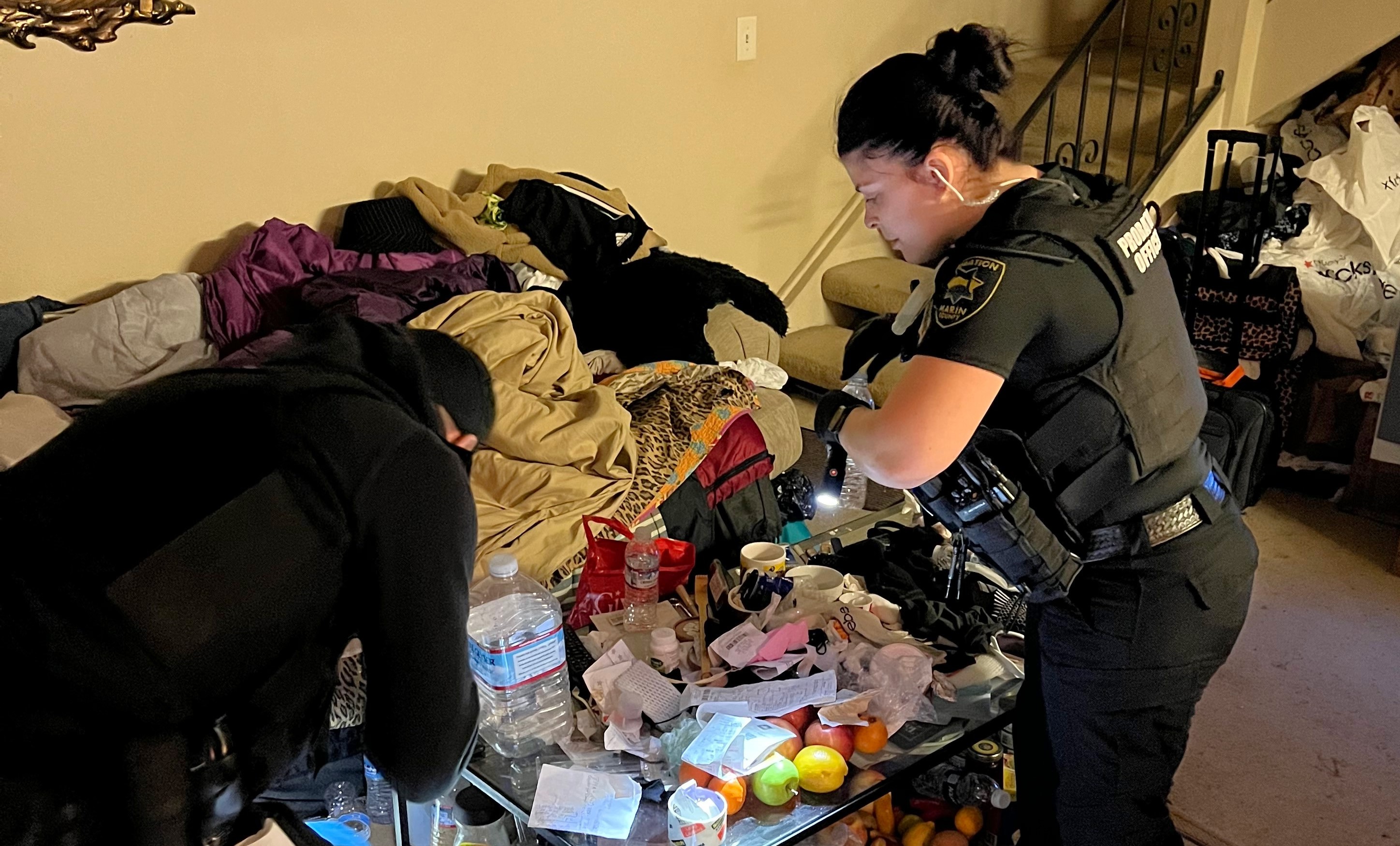 Two probation officers check belongs of a former DUI offender for evidence of alcohol or drugs.