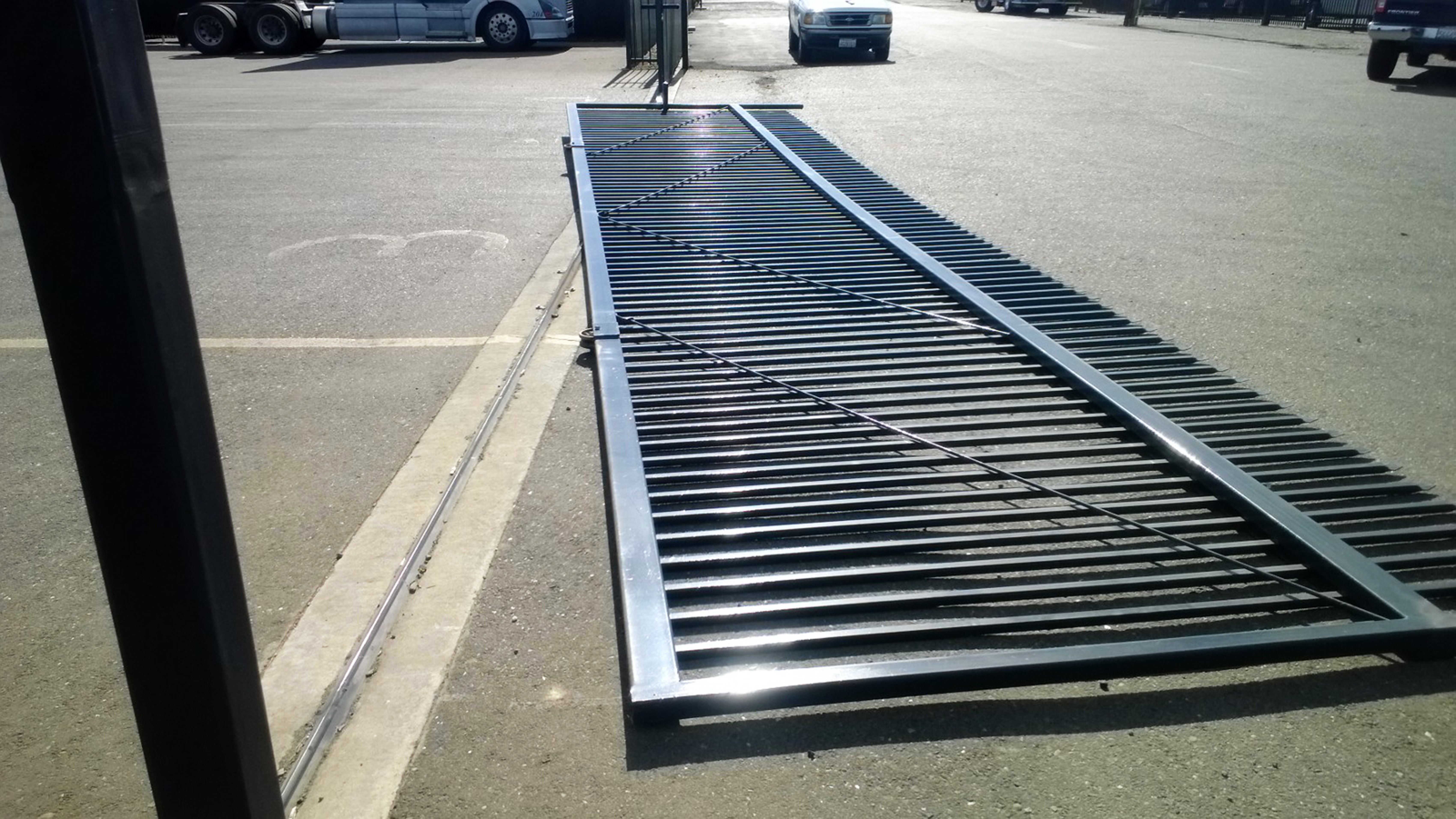 A large heavy metal gate lies on the ground after dislodging from a stand-up position.