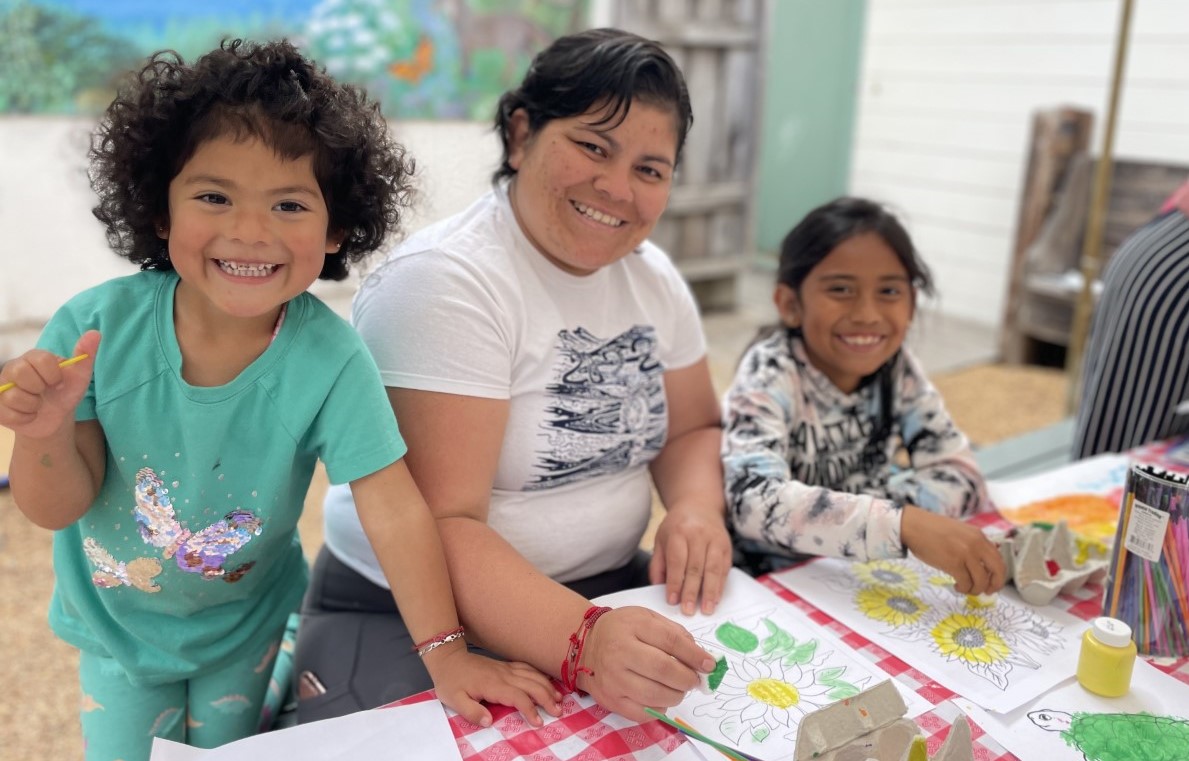 A mother and two young kids paint at a library.