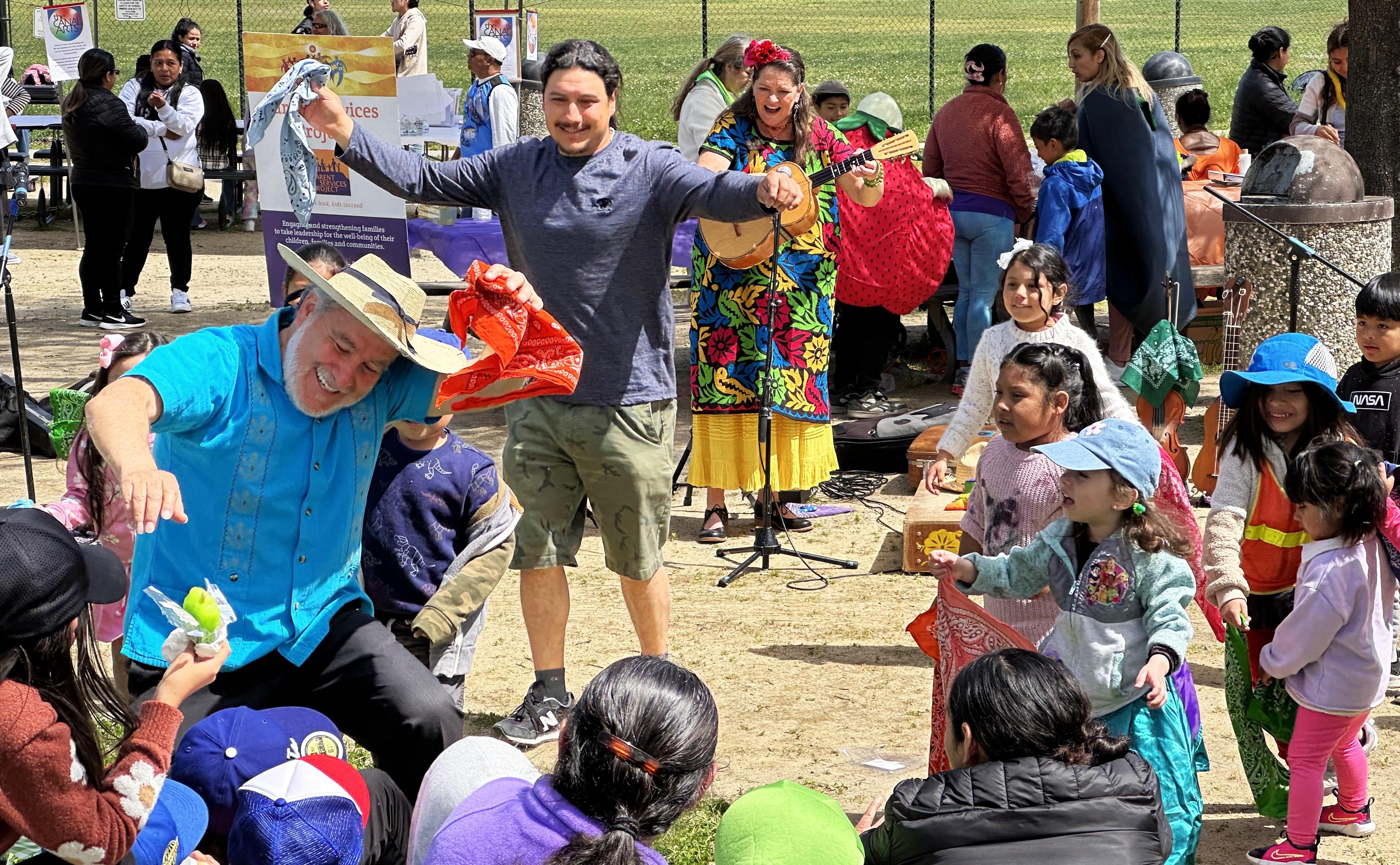 Several dozen people smile and have a good time at an outdoor library event.
