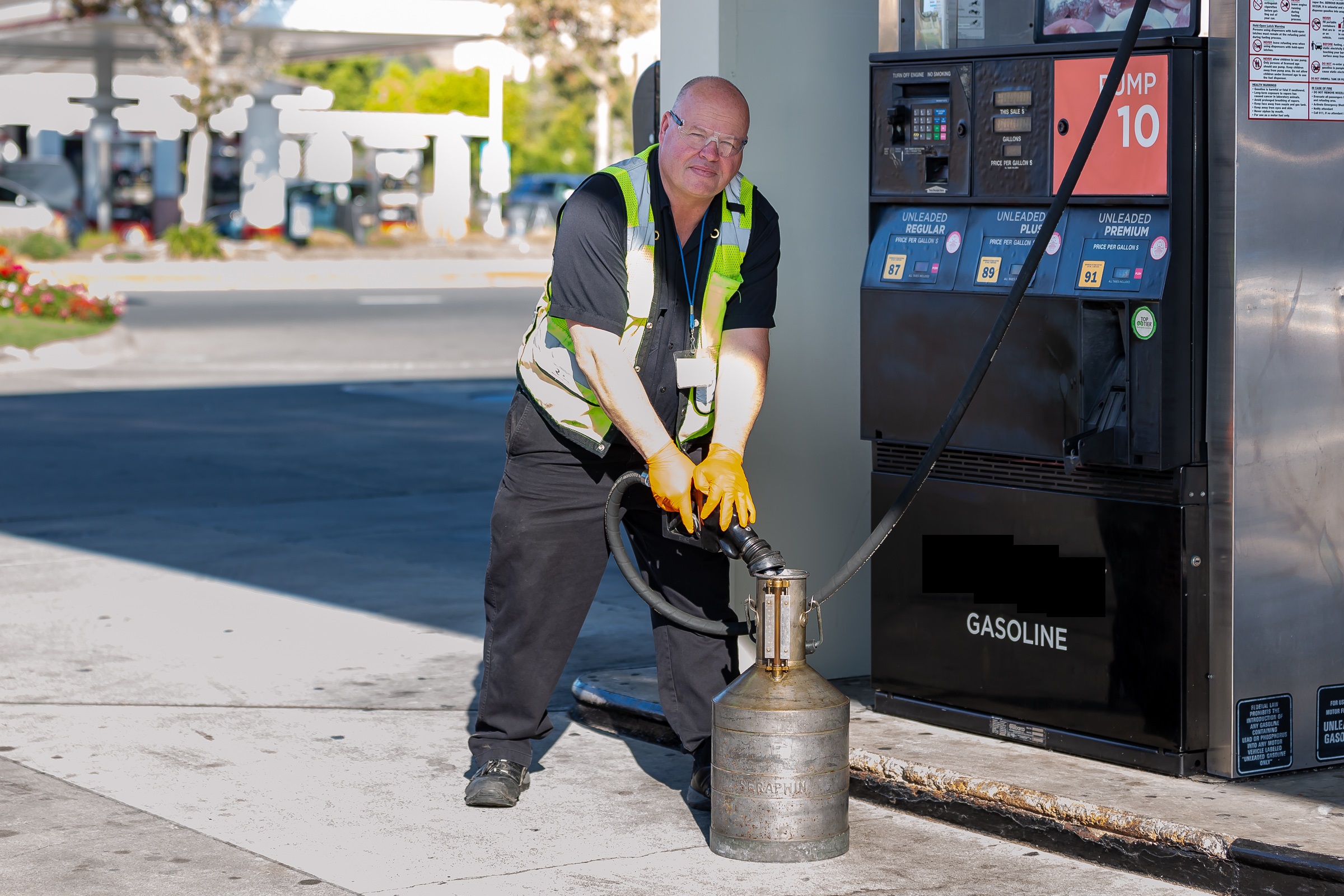 A male inspector checks the volume of a gallon of gas at a gas station.