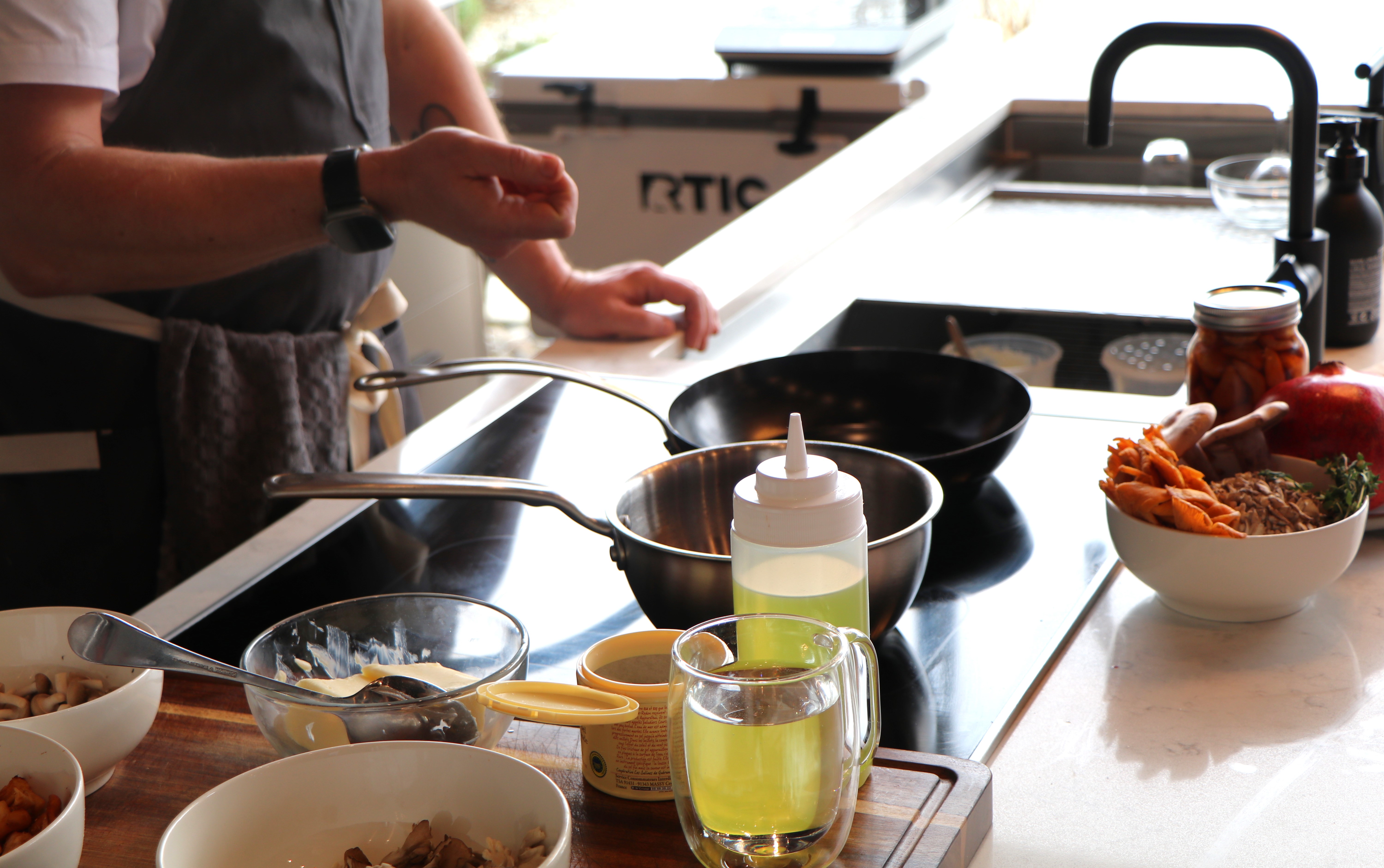 The hands of a cook are shown working with ingredients on a stovetop.