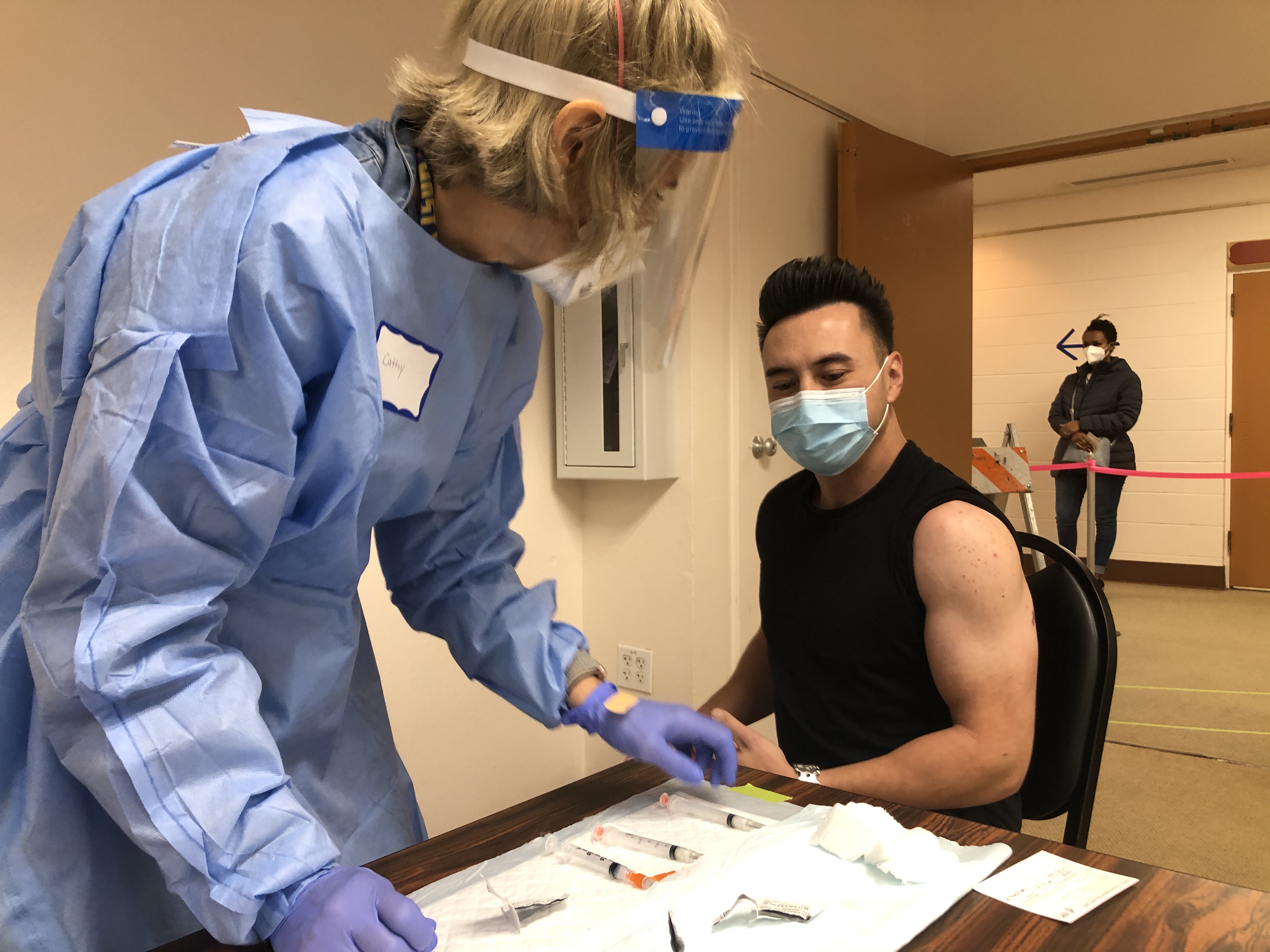 A young man prepares for a nurse to give him a COVID-19 vaccine.