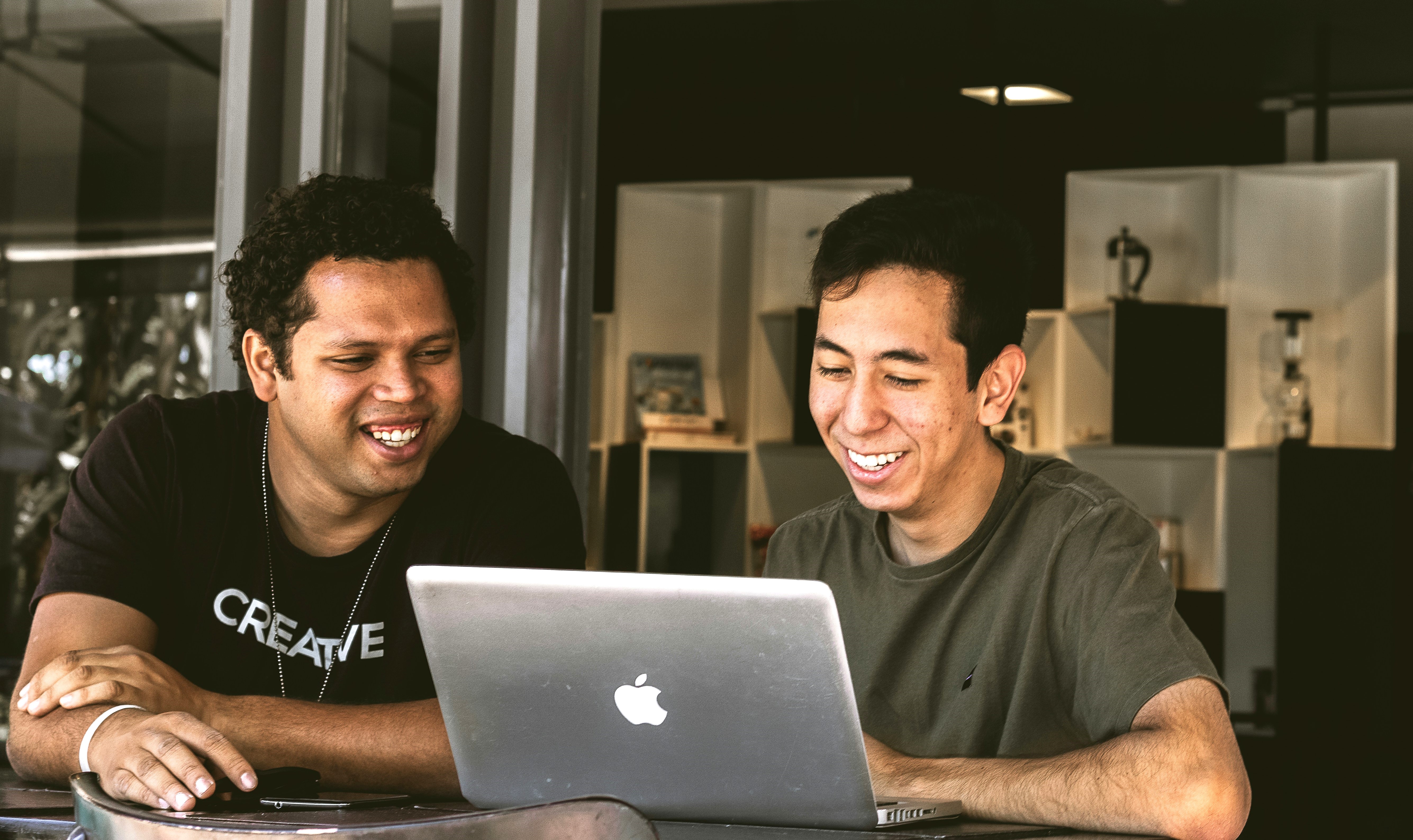 Two men smile as they look at a computer screen at a business.