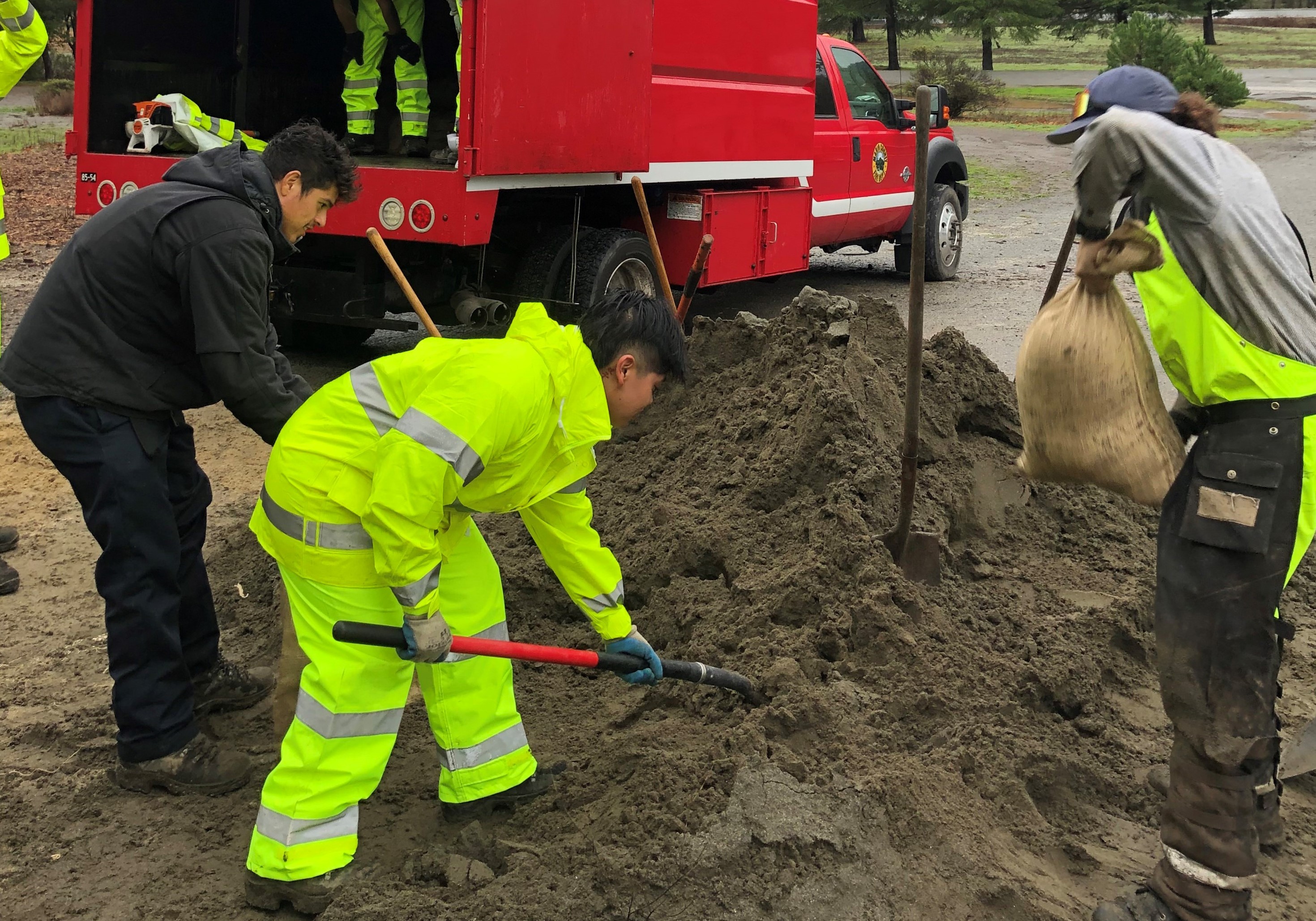FIRE Foundry workers shovel sand to make sandbags.