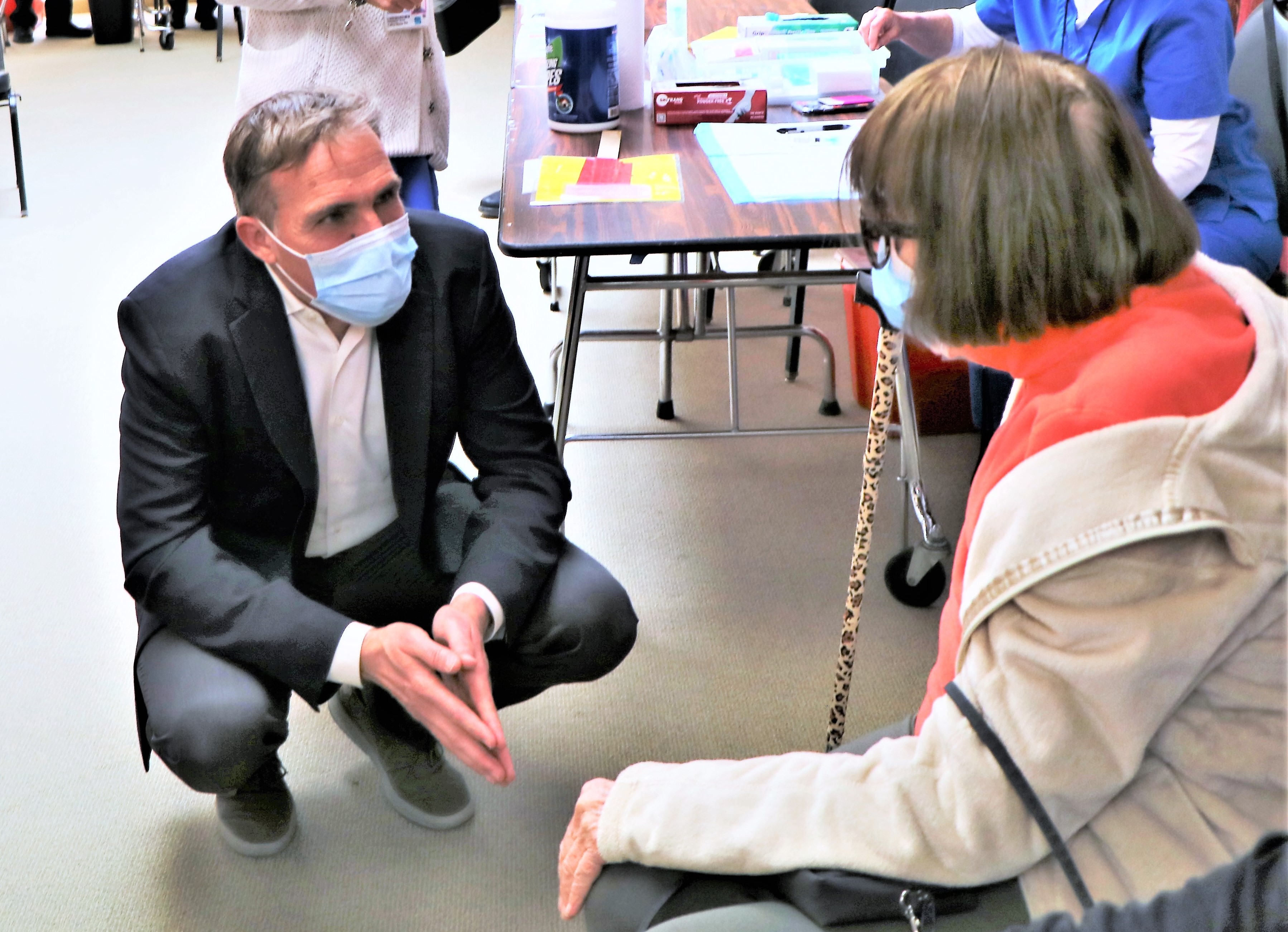 Dr. Matt Willis, wearing a protective mask, speaks to a woman who is about to be vaccinated against COVID-19.