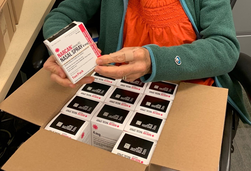 A person's hands hold up a box of Narcan spray.