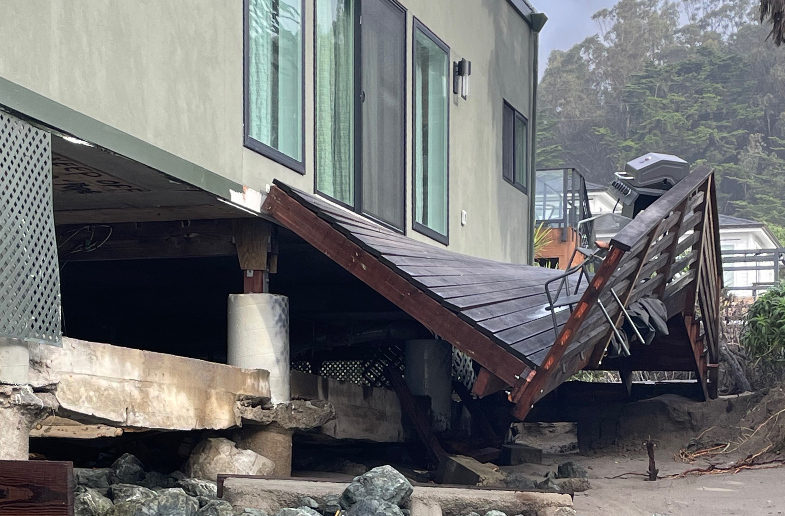 A damaged wooden deck on the side of a house.