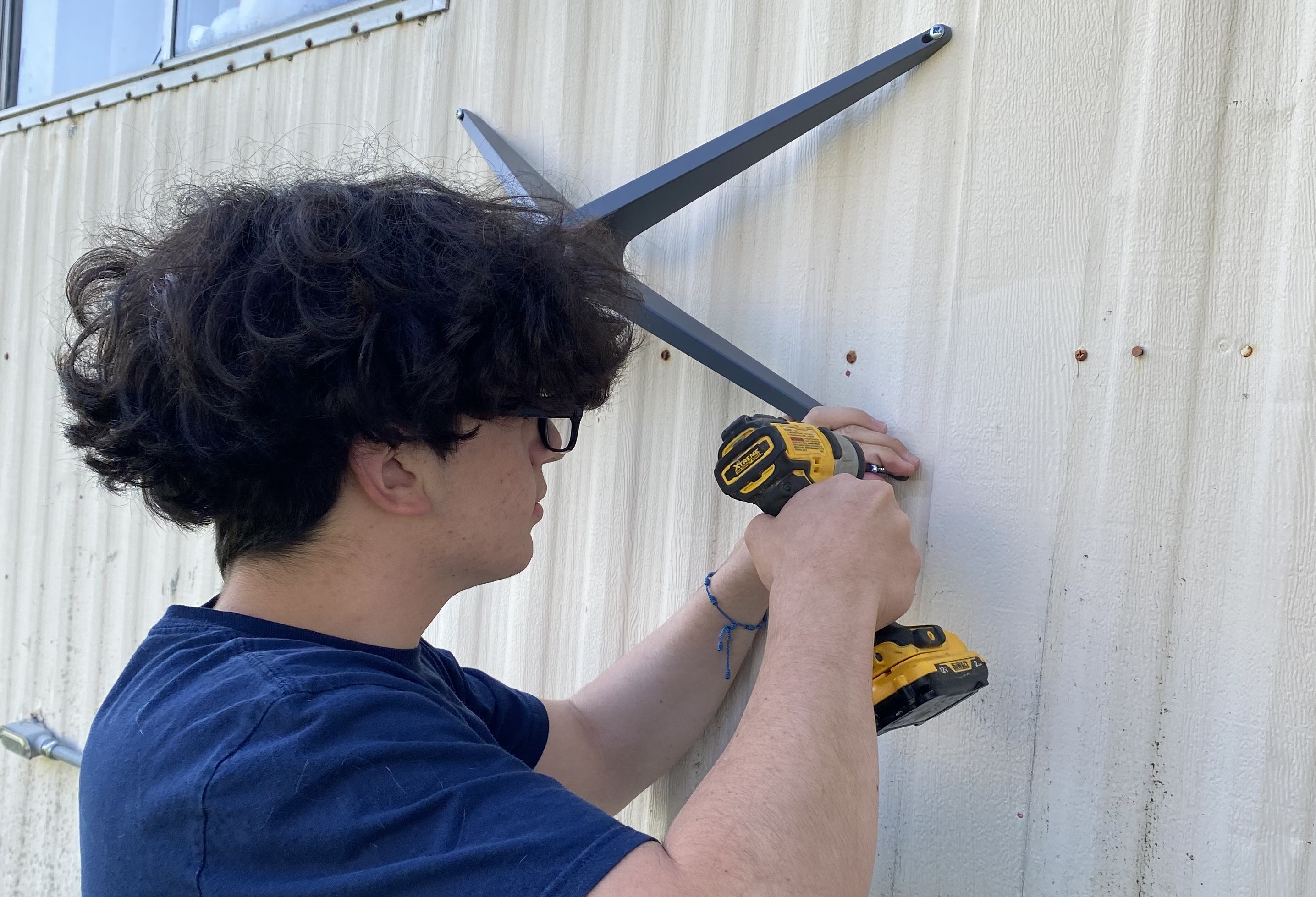 A young man screws in a broadband device to the site of a building.