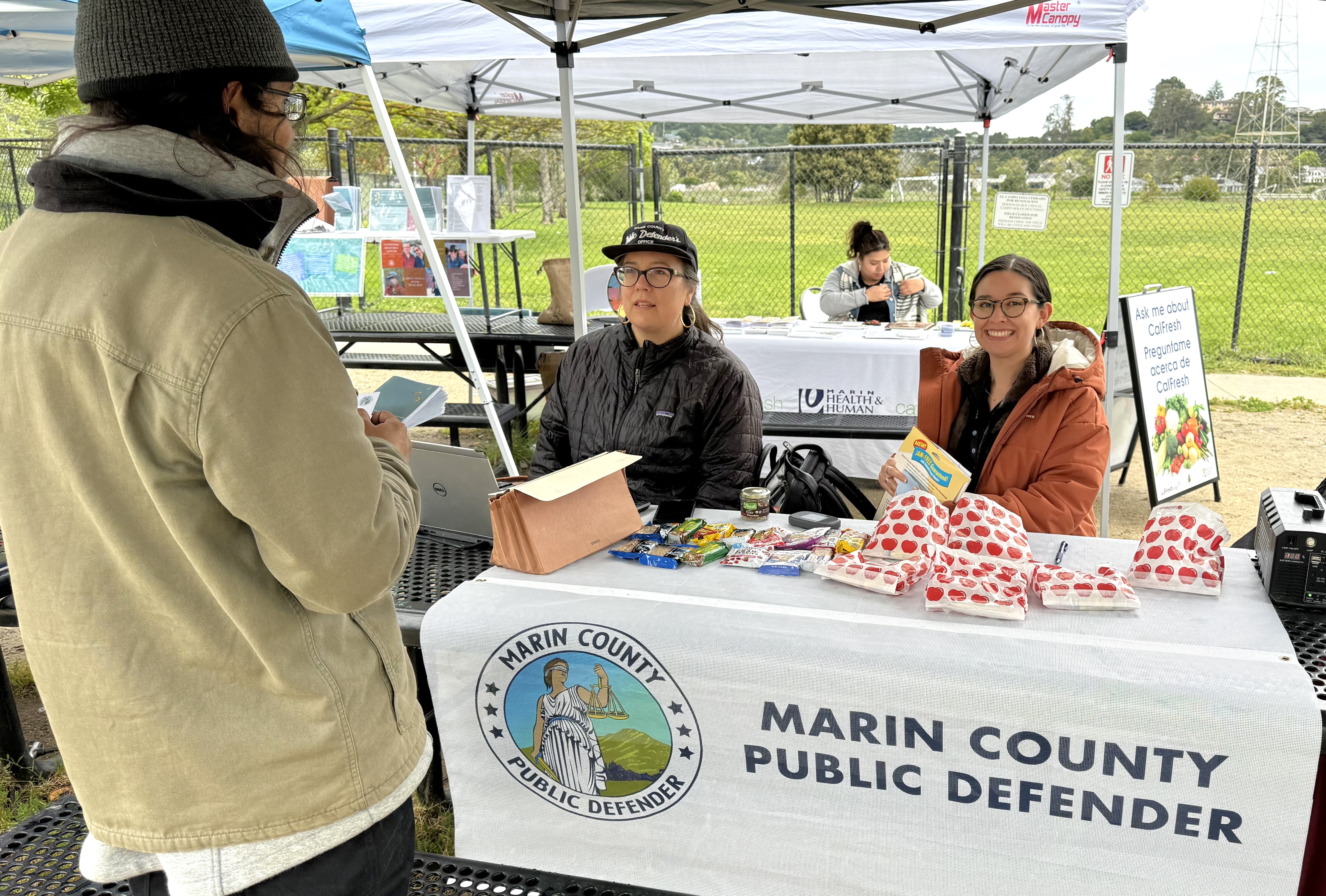 Two women seated at a table assist a man at the Clean Slate event.