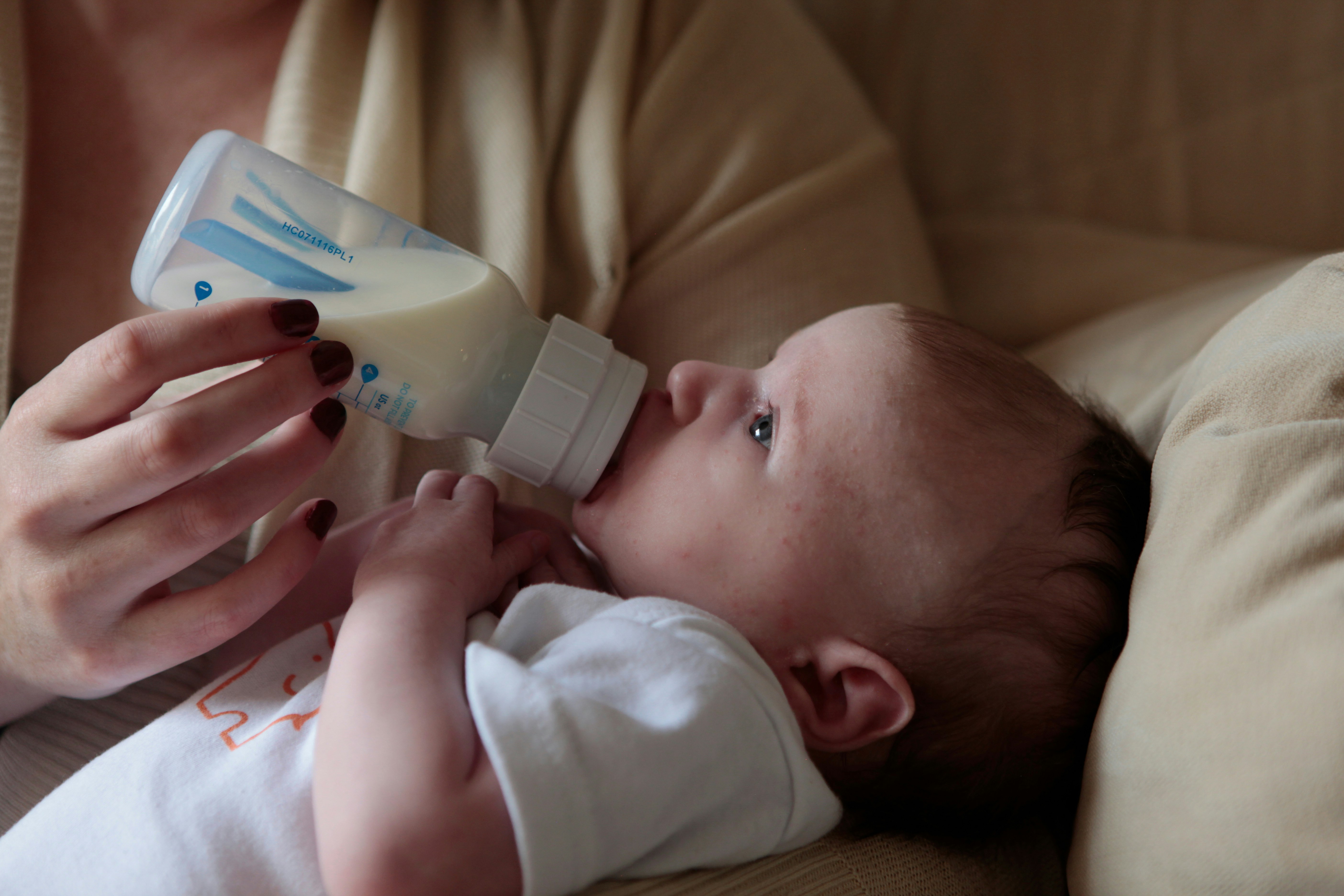 A closeup view of a baby getting fed by a bottle.