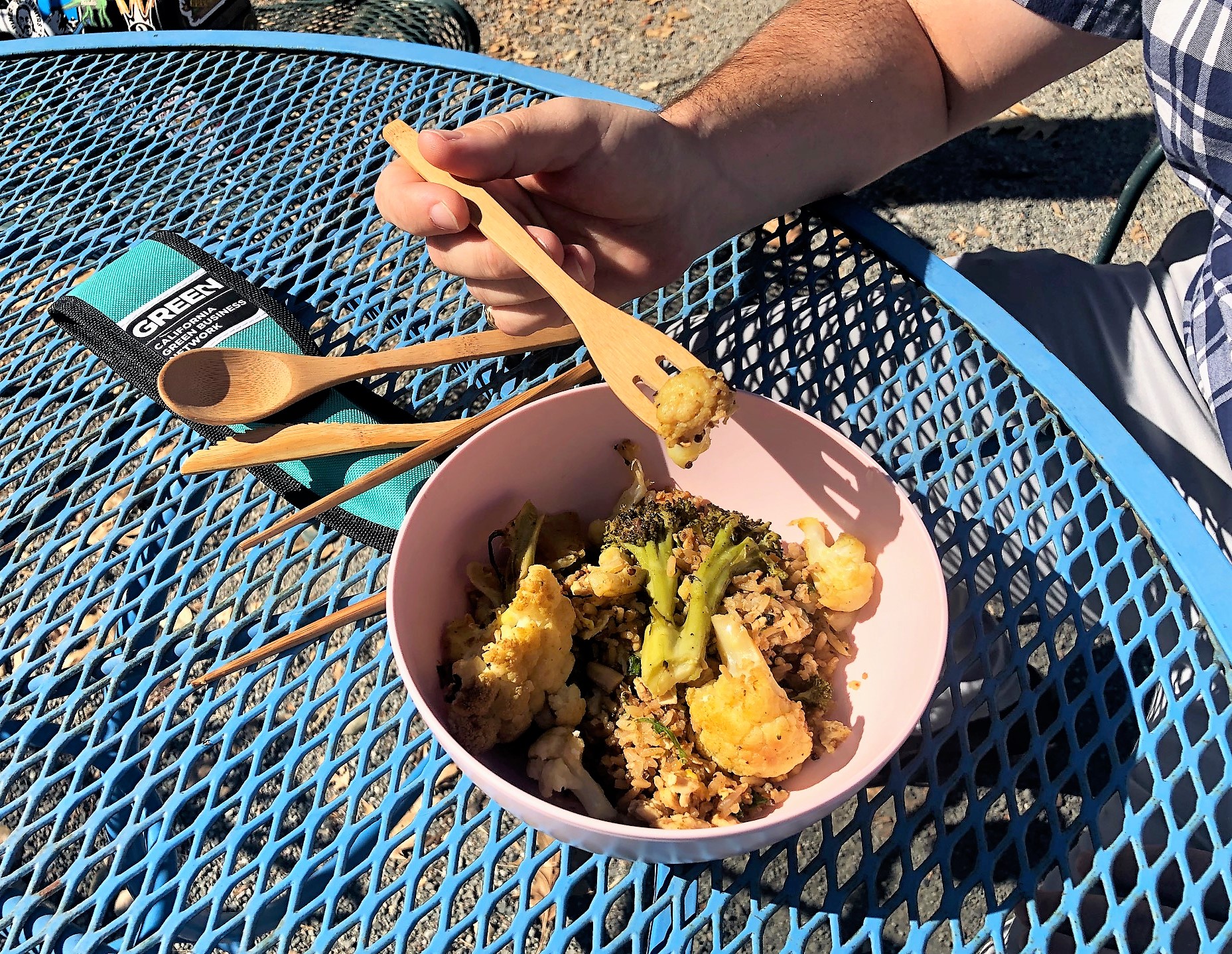 A closeup view of a person's hands eating lunch with wooden utensils.