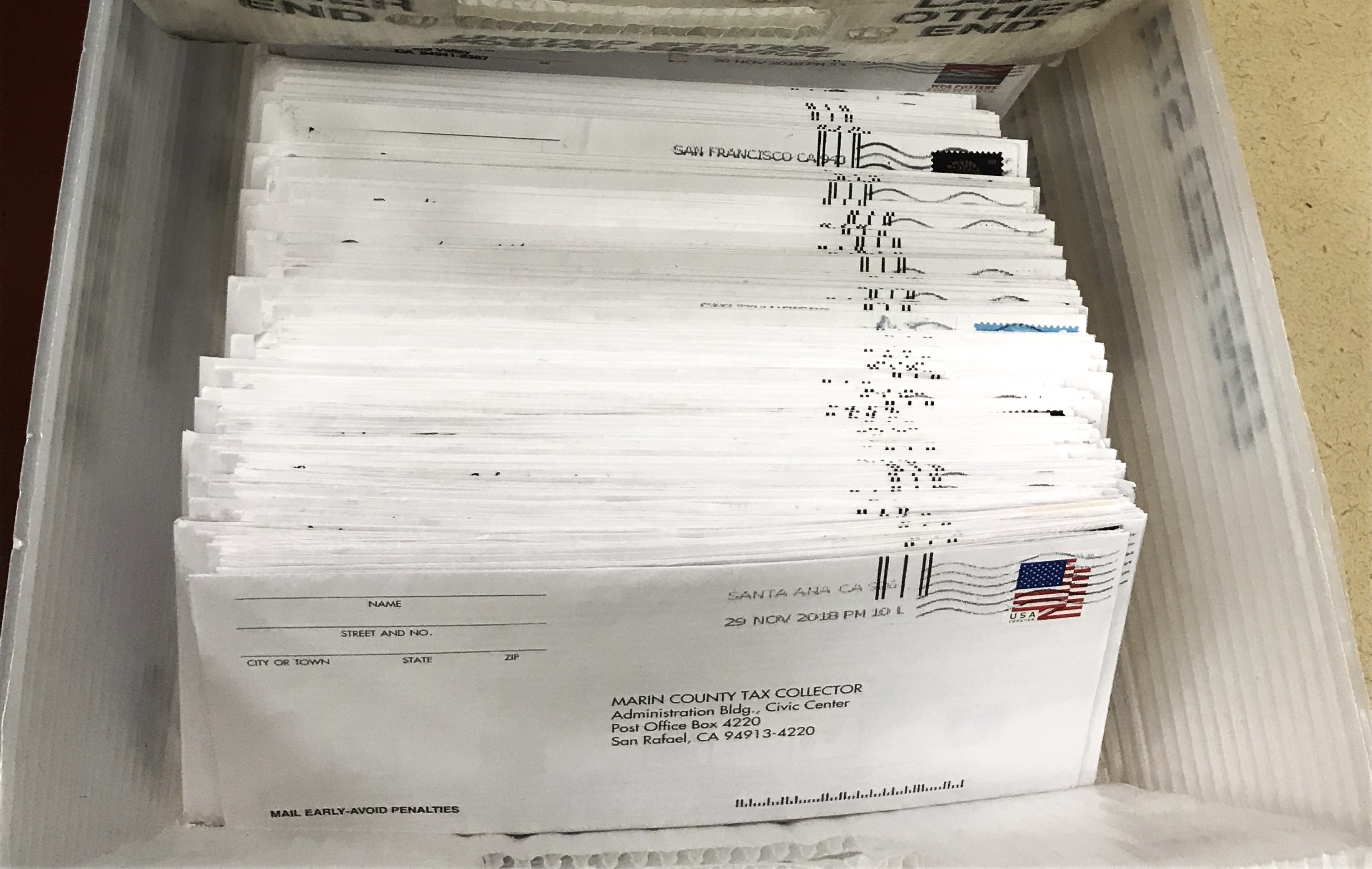 A stack of envelopes with property tax bills sits in a crate.