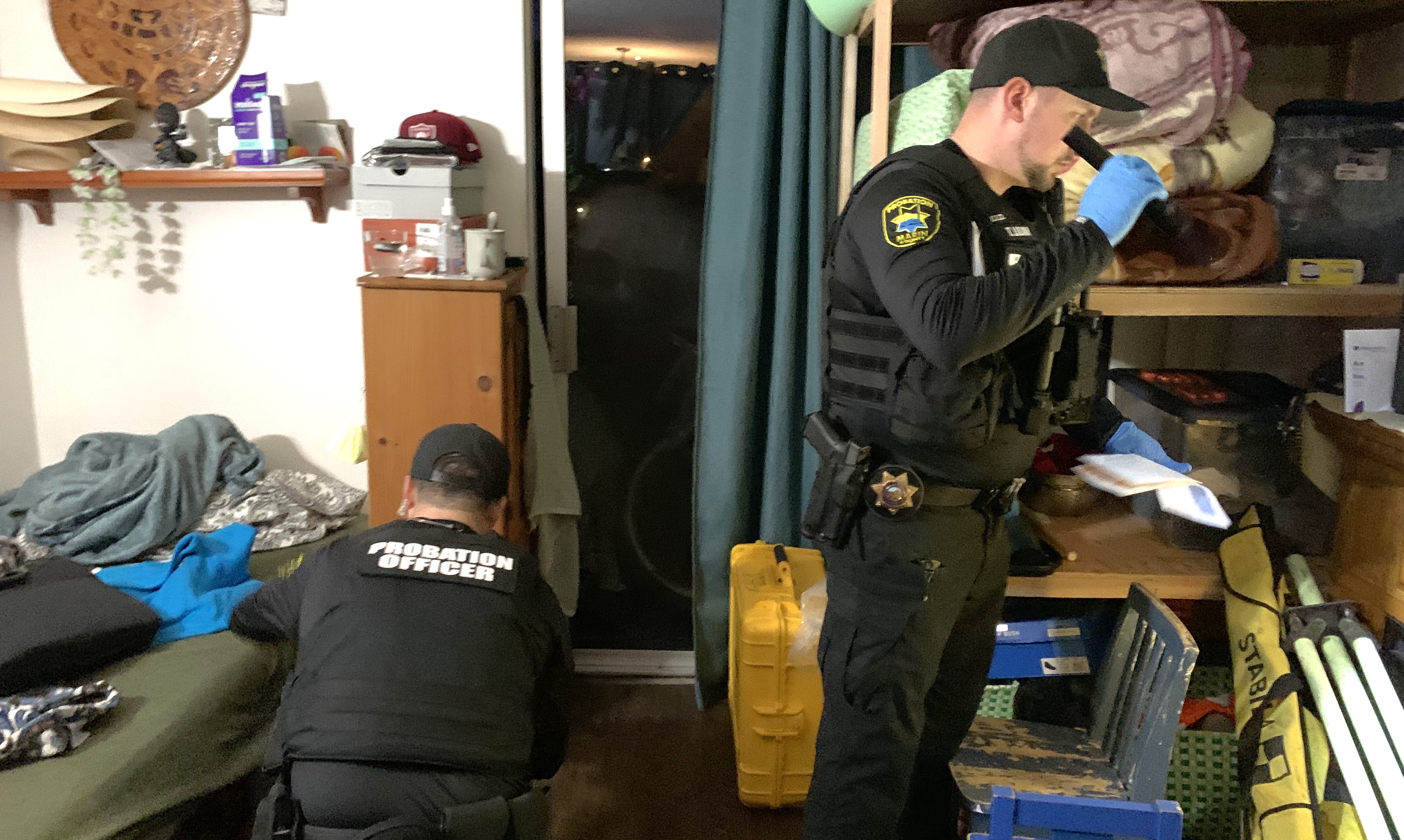 Two Probation officers check a person's bedroom for drugs or alcohol.