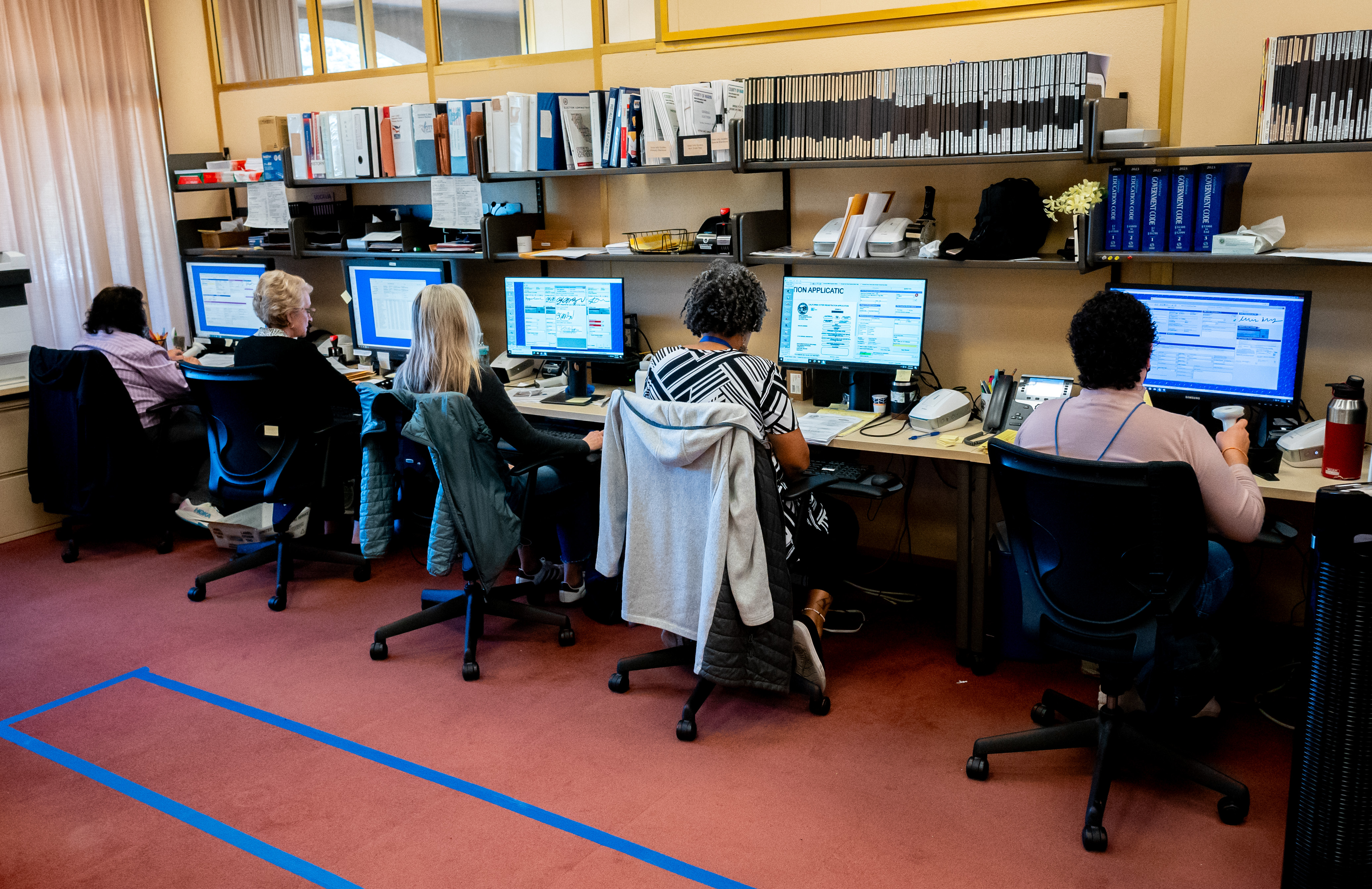 Five employees work at computers at the Elections Department.