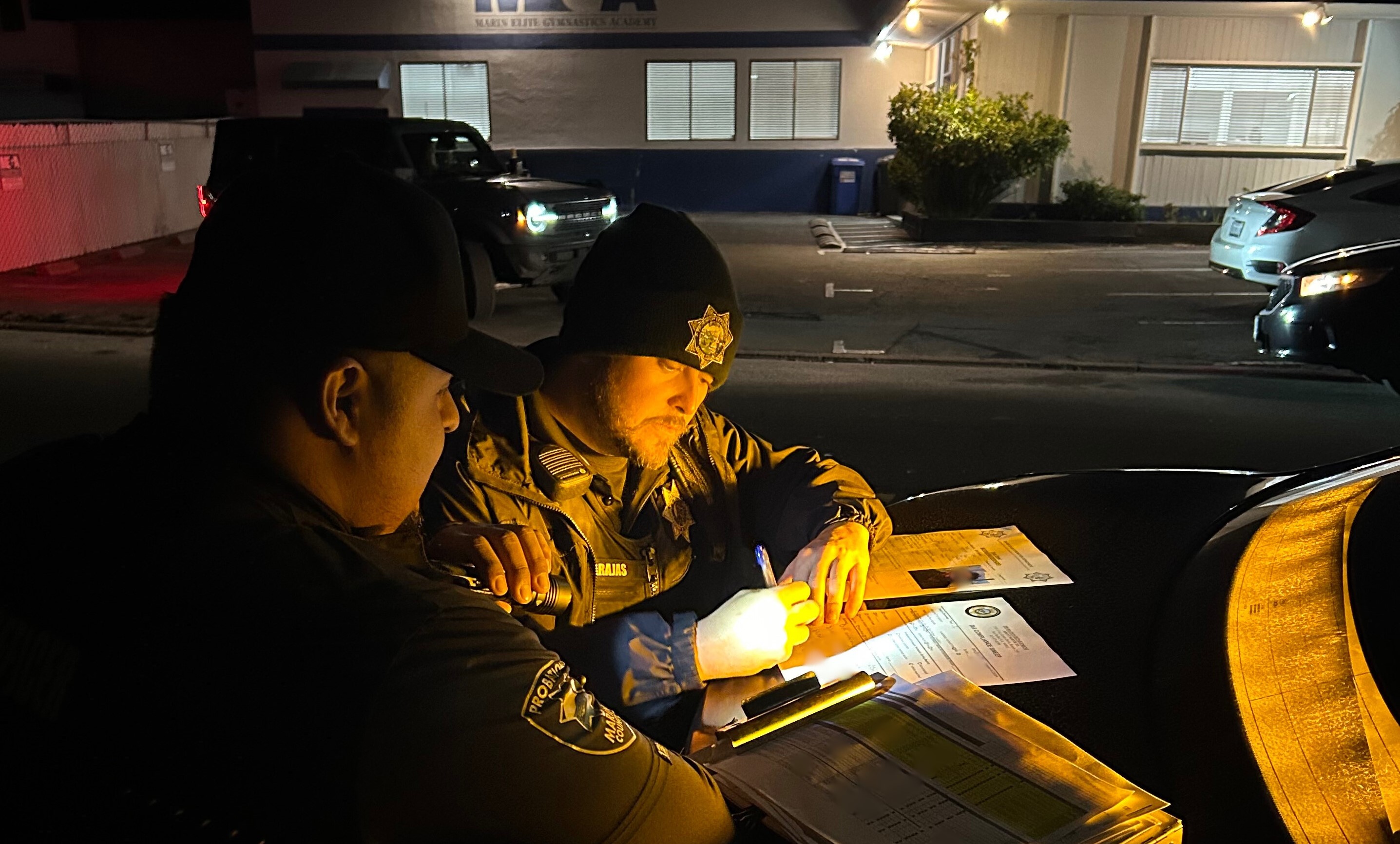 Two probation officers confer outside an offender's residence during a compliance check.