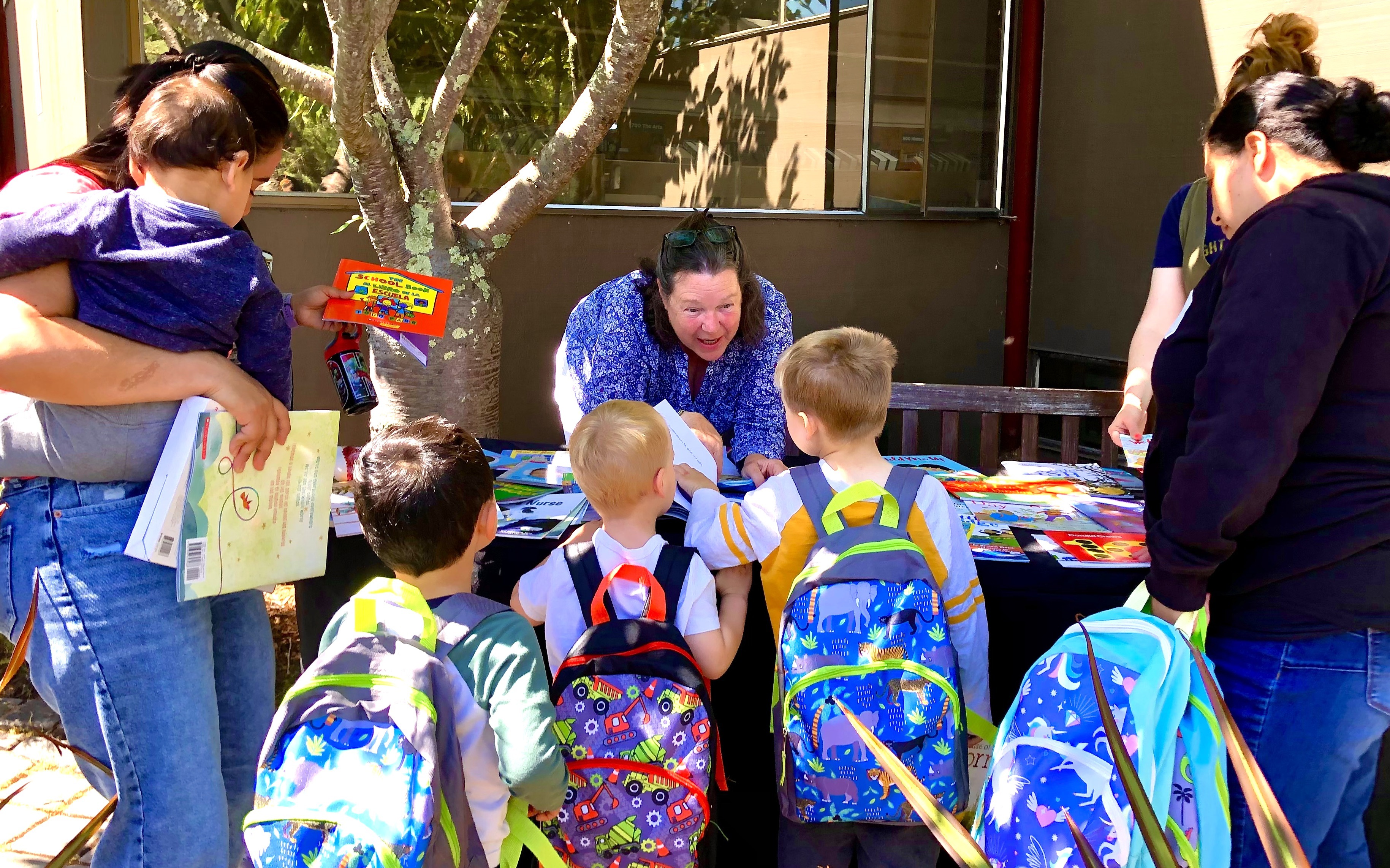 A child care teacher leans over and speaks to some young children.