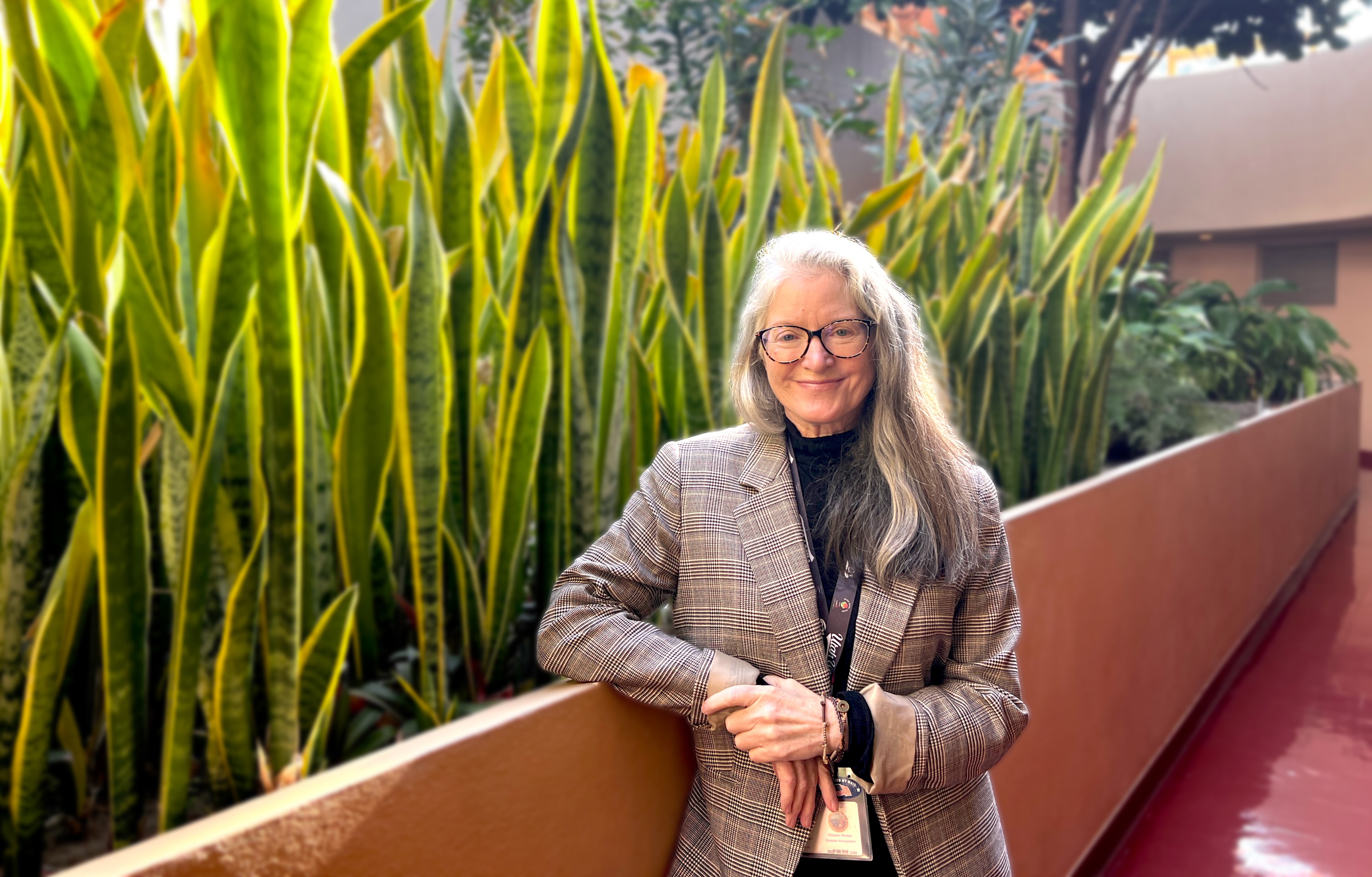 Lynda Roberts poses in the Civic Center hallway with plants behind her.