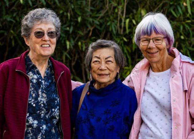 Three femaile volunters with the meals program stand together.