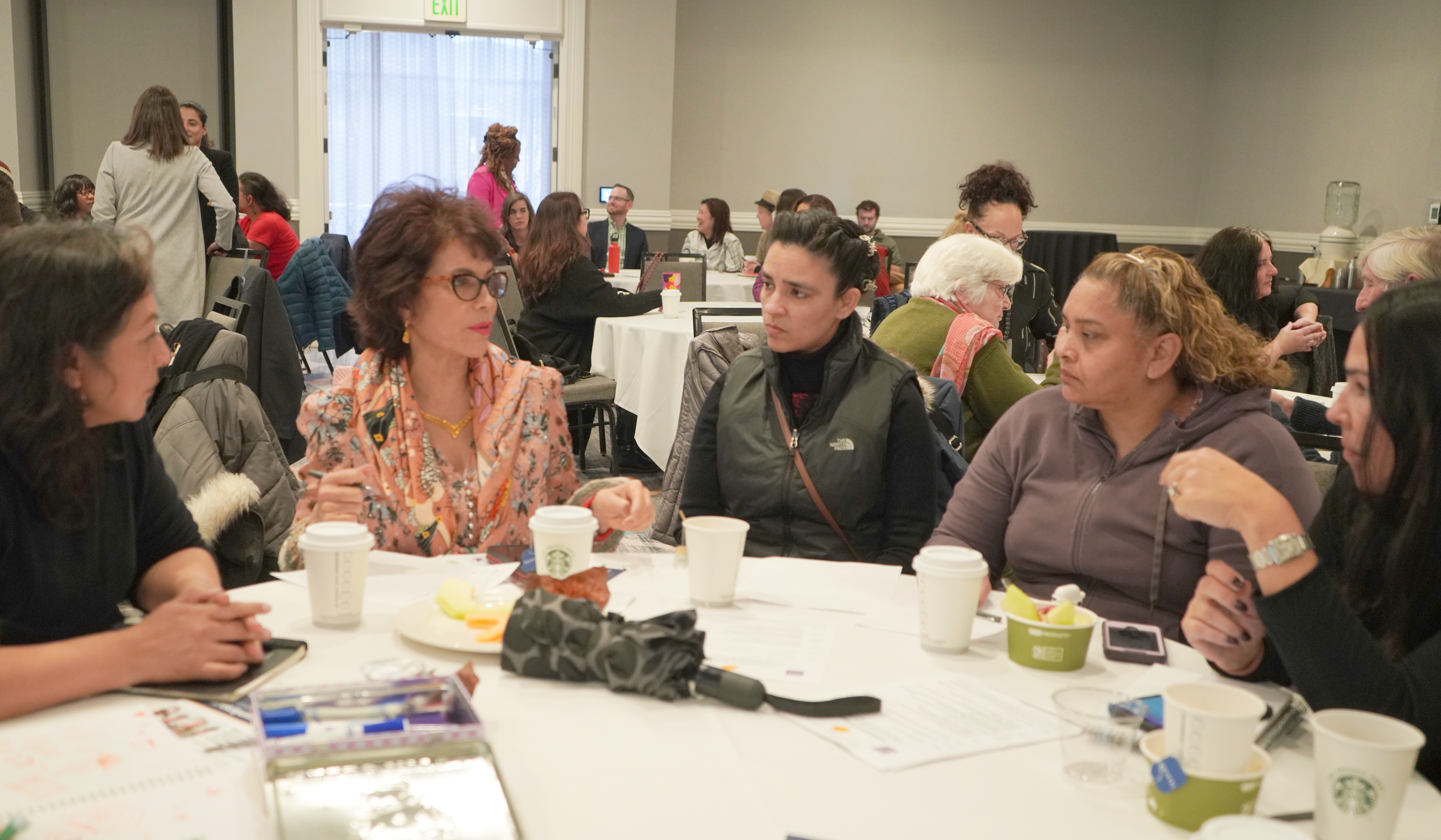 Four women seated at a table discuss immigration rights.