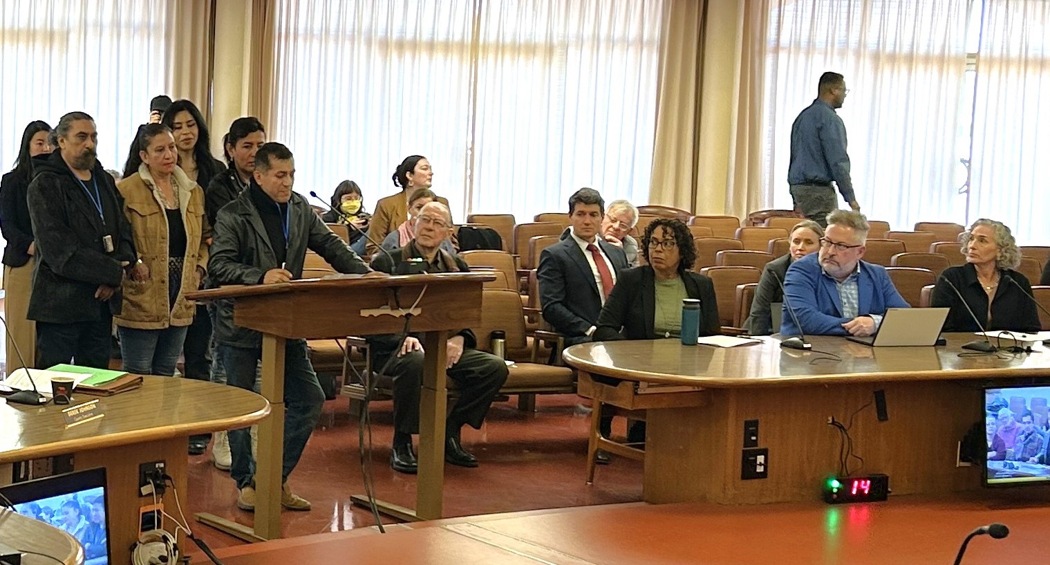 People are lined up at the microphone during a Board of Supervisors meeting about the shelter crisis declaration.