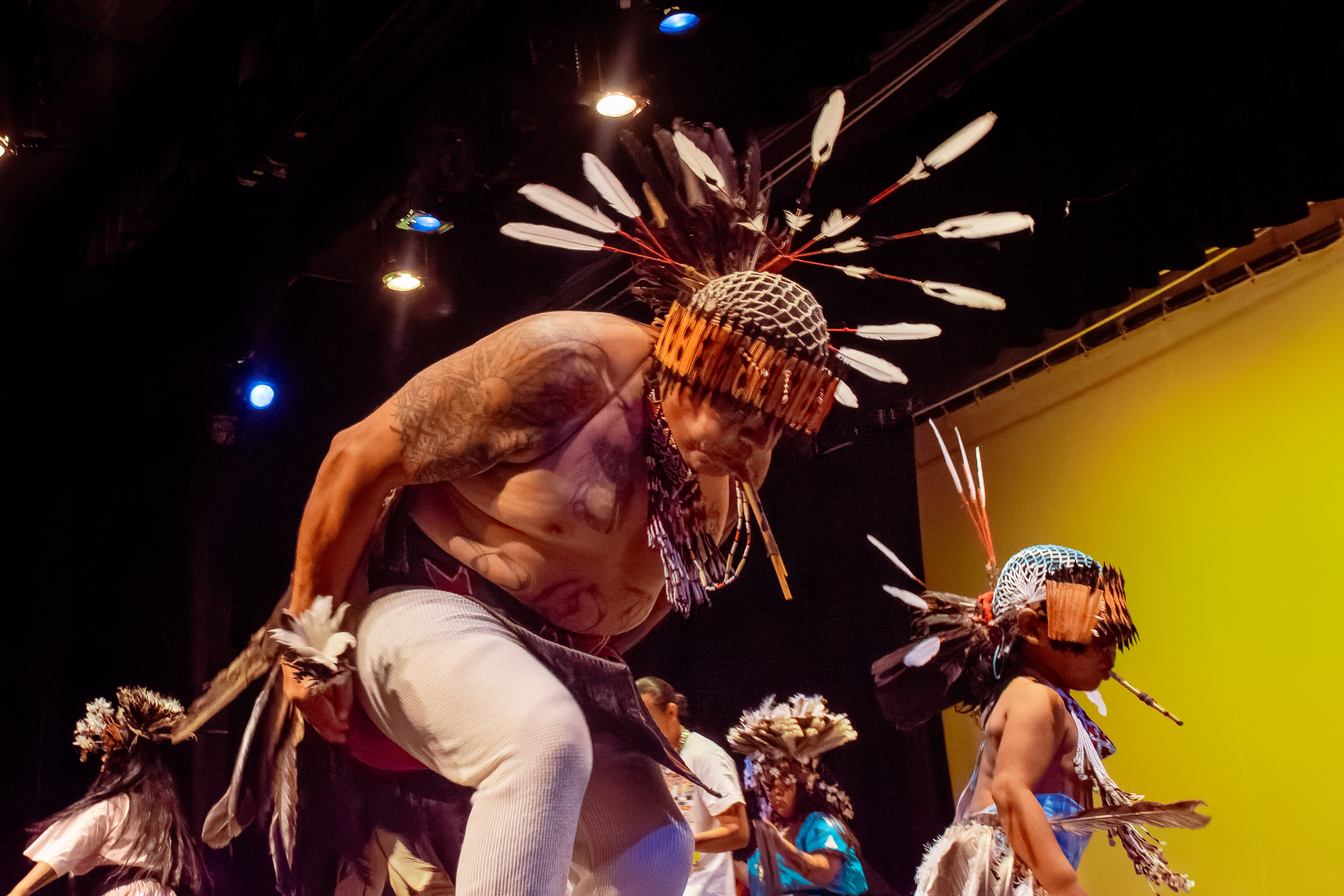 Two native Coastal Miwok dancers, an older man and a young girl, perform on stage. 
