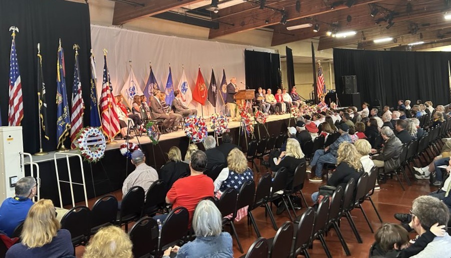 A large gruup of spectators watch a ceremony on stage at Memorial Day 2024.