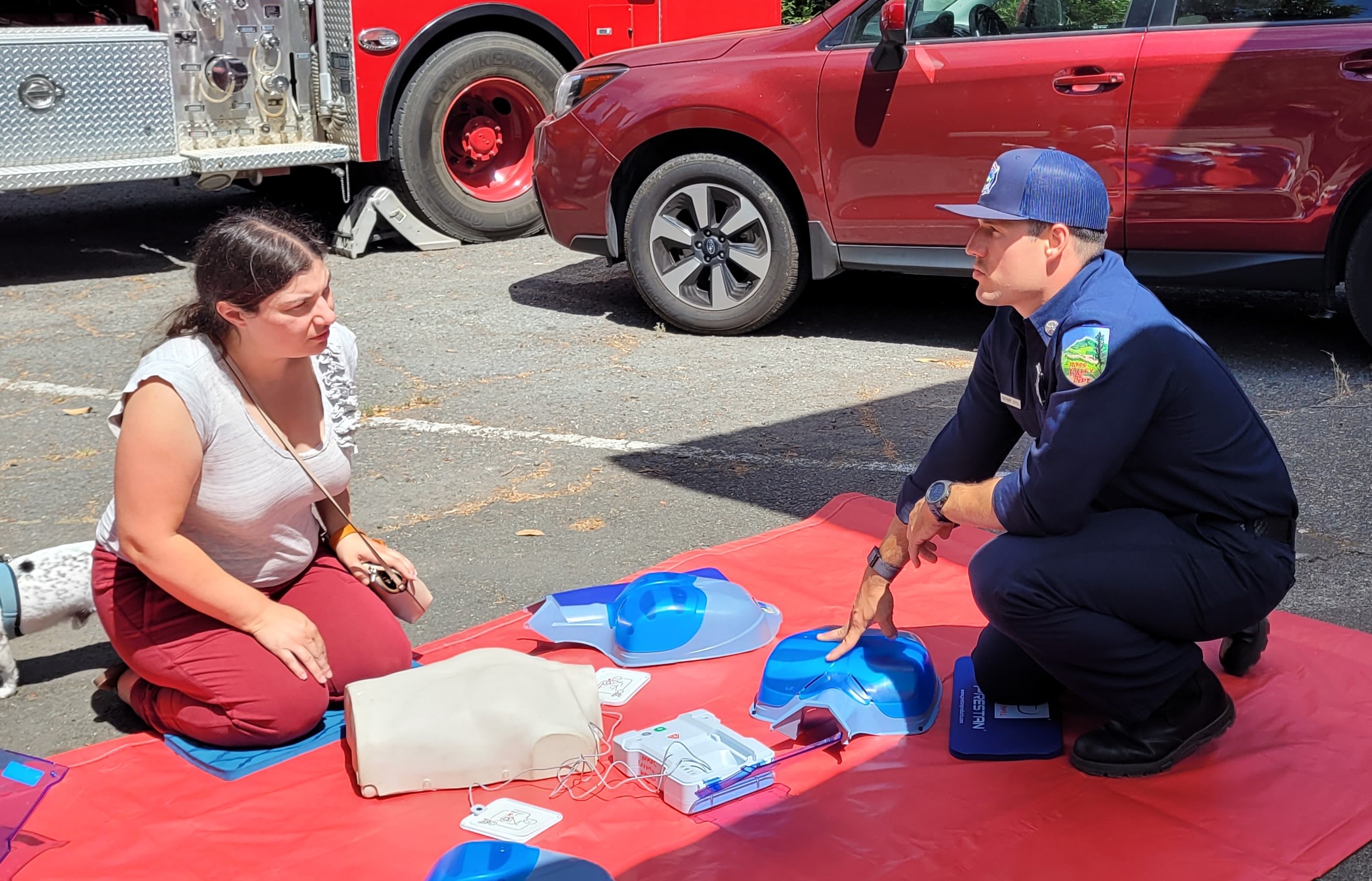 A woman receives CPR training from a firefighter.