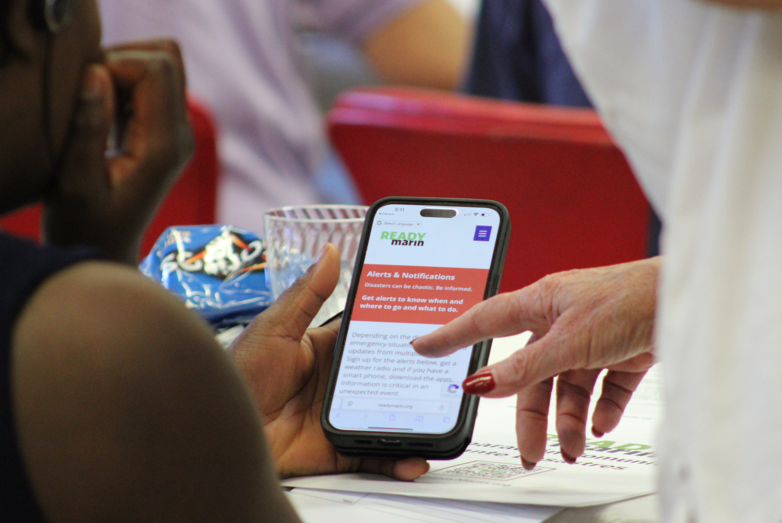 Two people look at a phone that has the ReadyMarin app open.