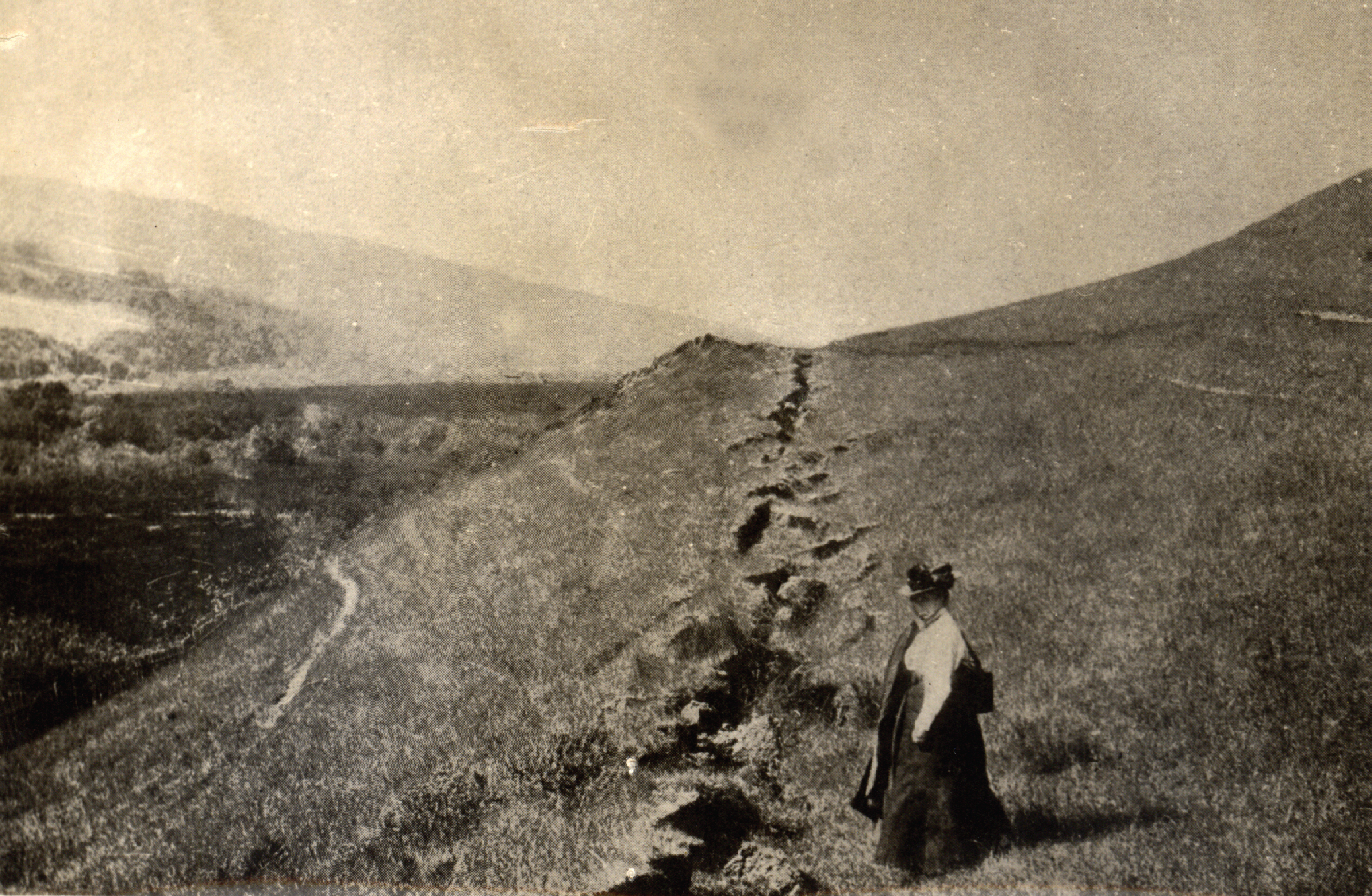 A woman stands next to an earthquake fissure after the 1906 quake in Marin County.
