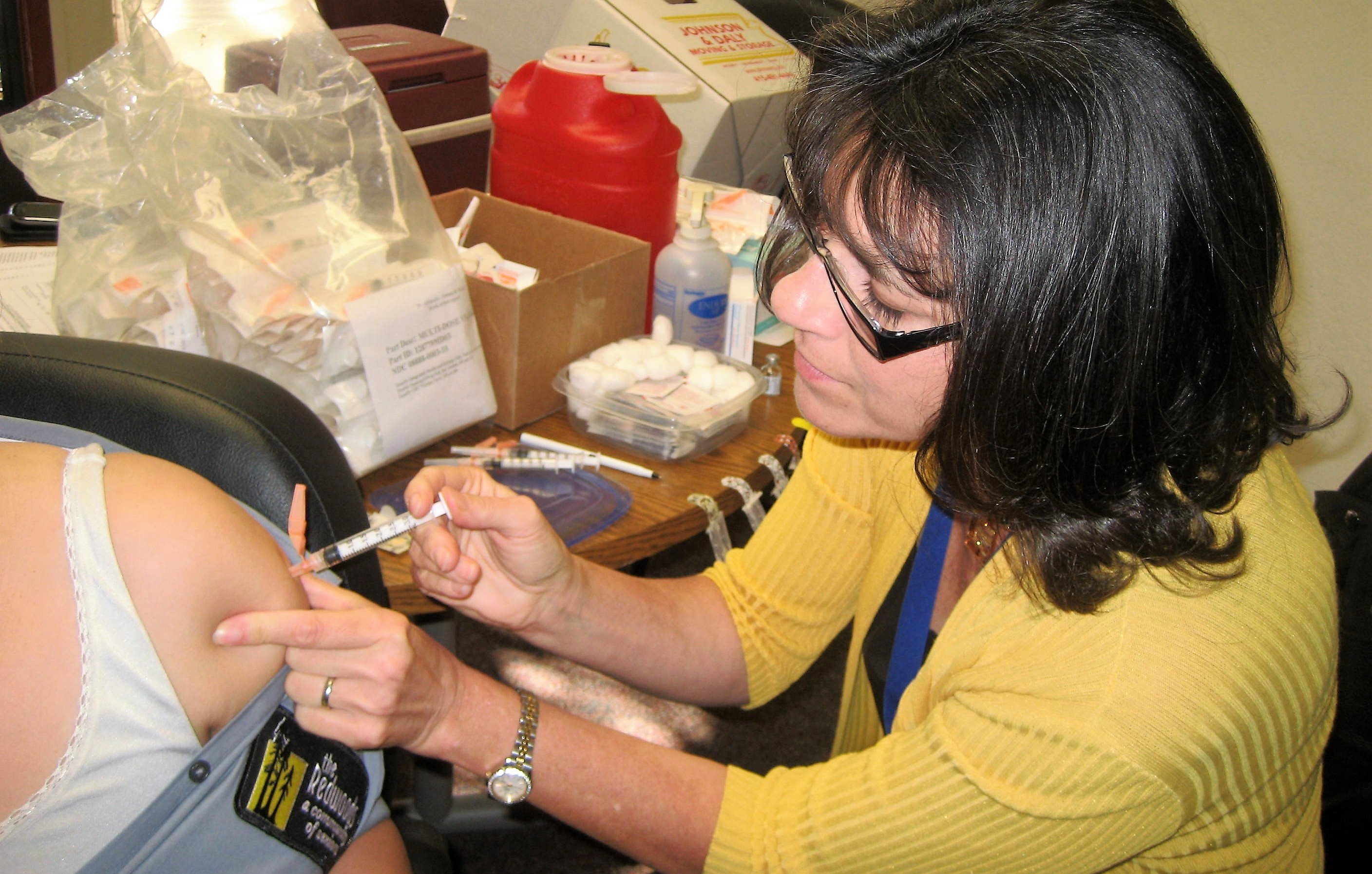 A female nurse injects a person with a vaccine.