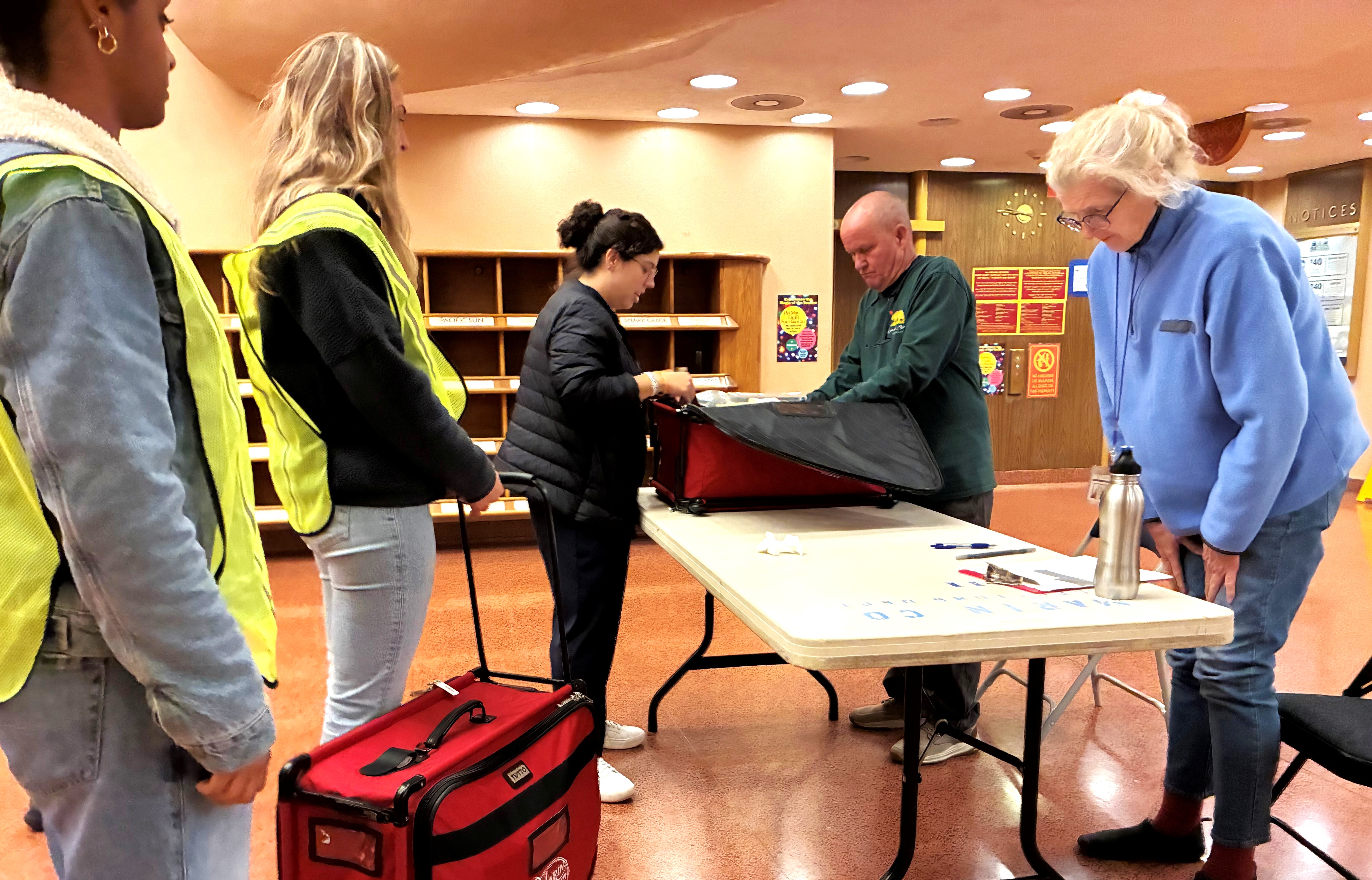 Several election workers bring back secured ballots from the vote center.