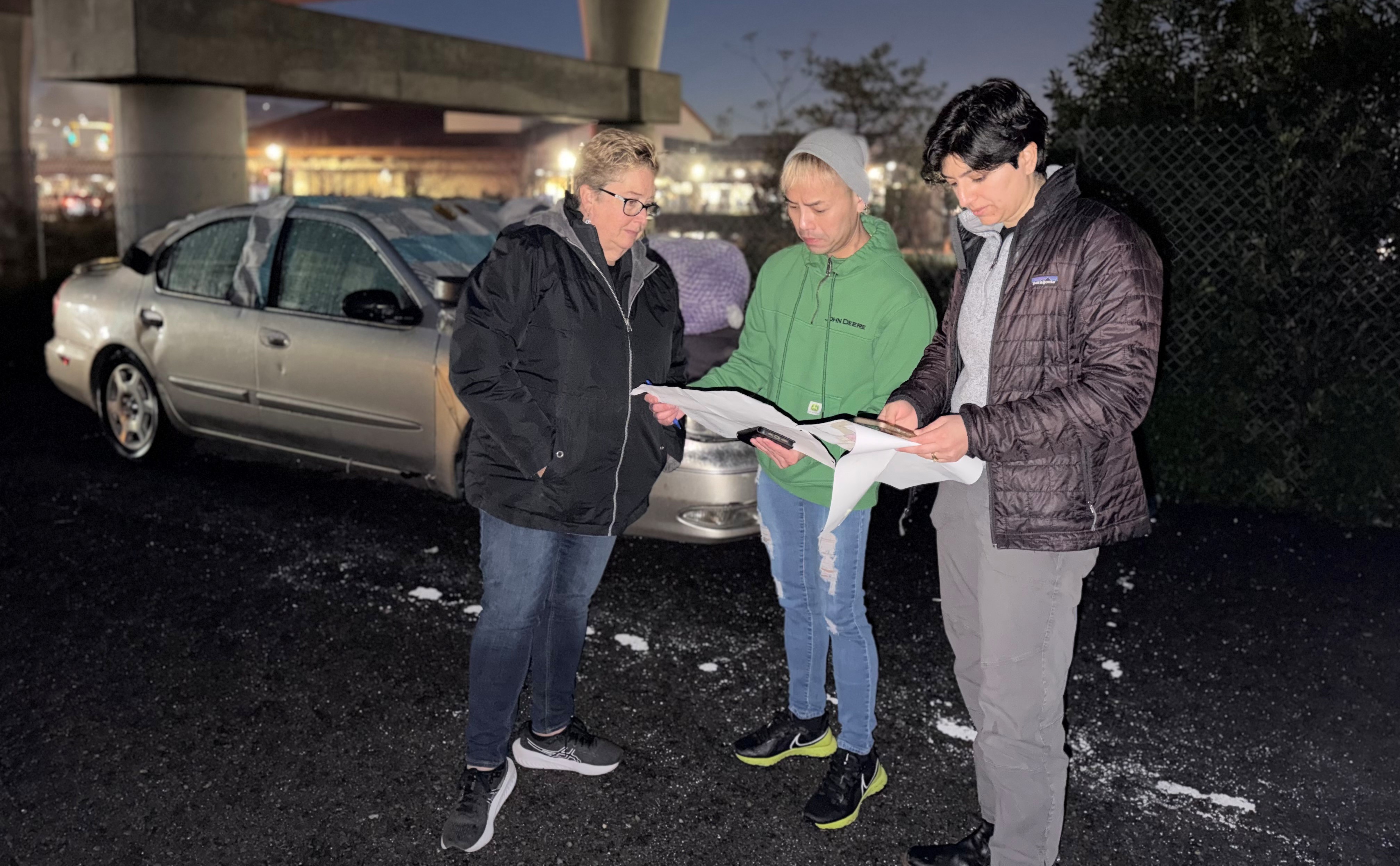 Three people look at documents before assisting with the Point in Time Count in Marin County.