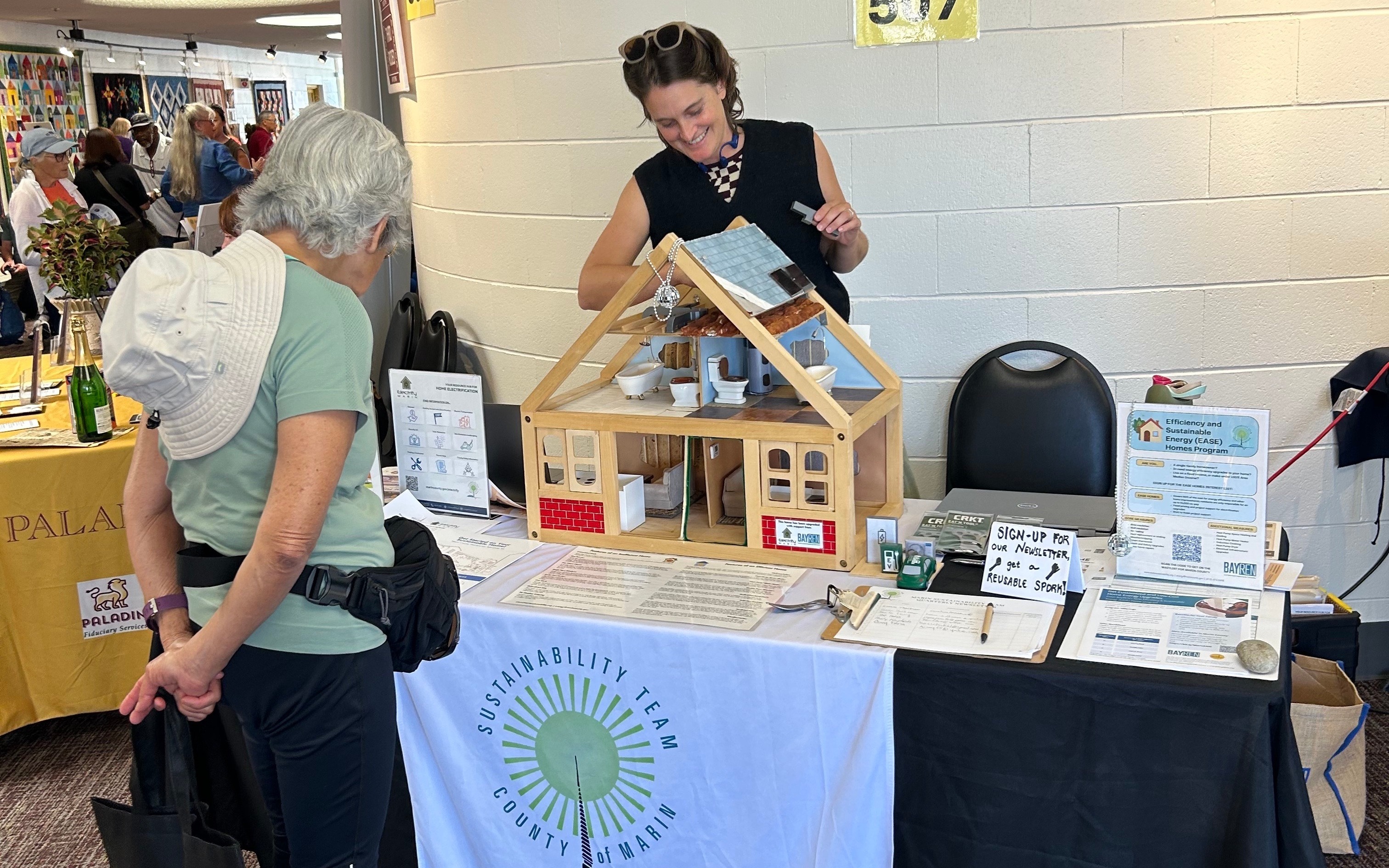 A woman from the Sustainability Team speaks with another woman at a promotional event.