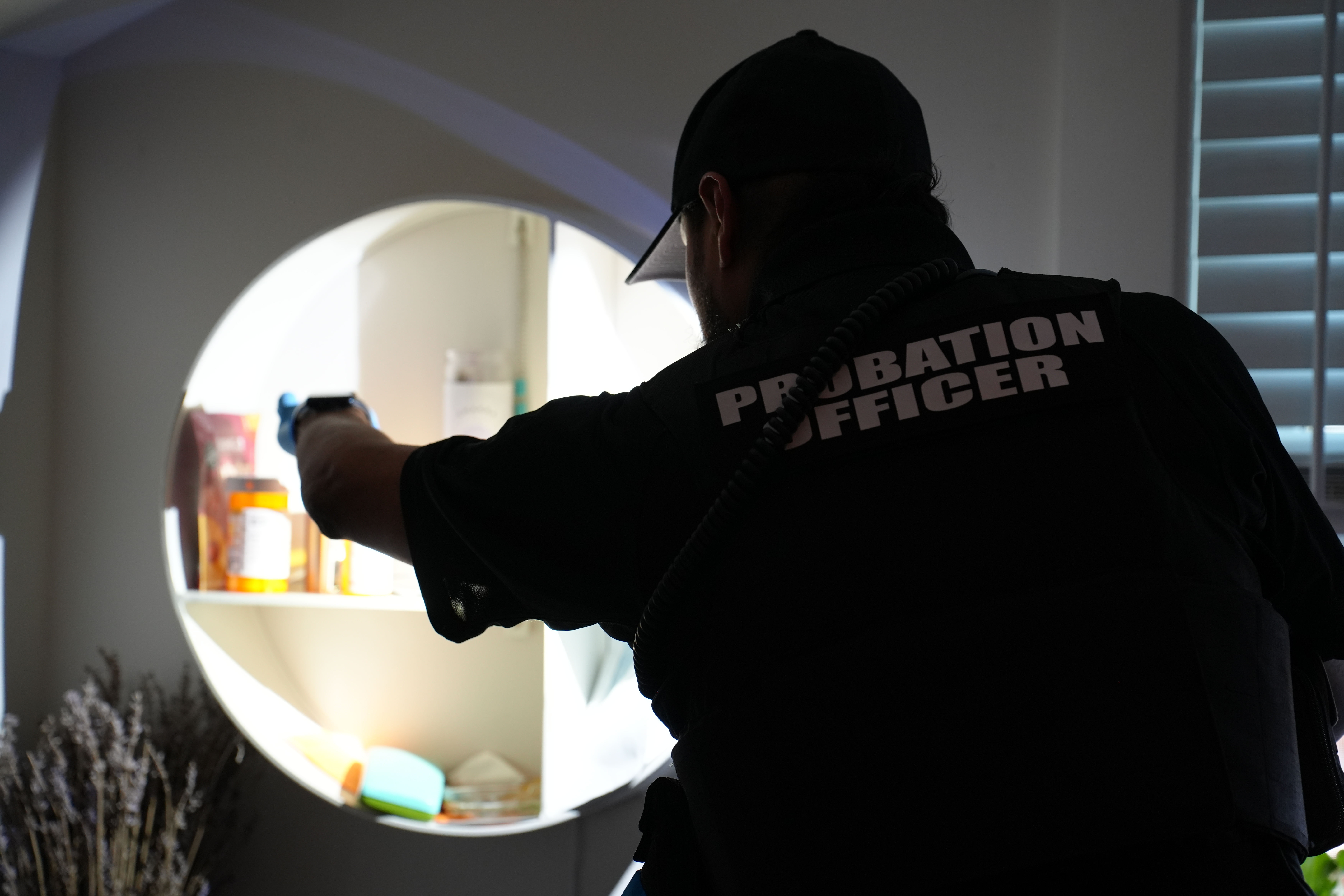 An officer shines a spotlight into a cabinet during a DUI enforcement.