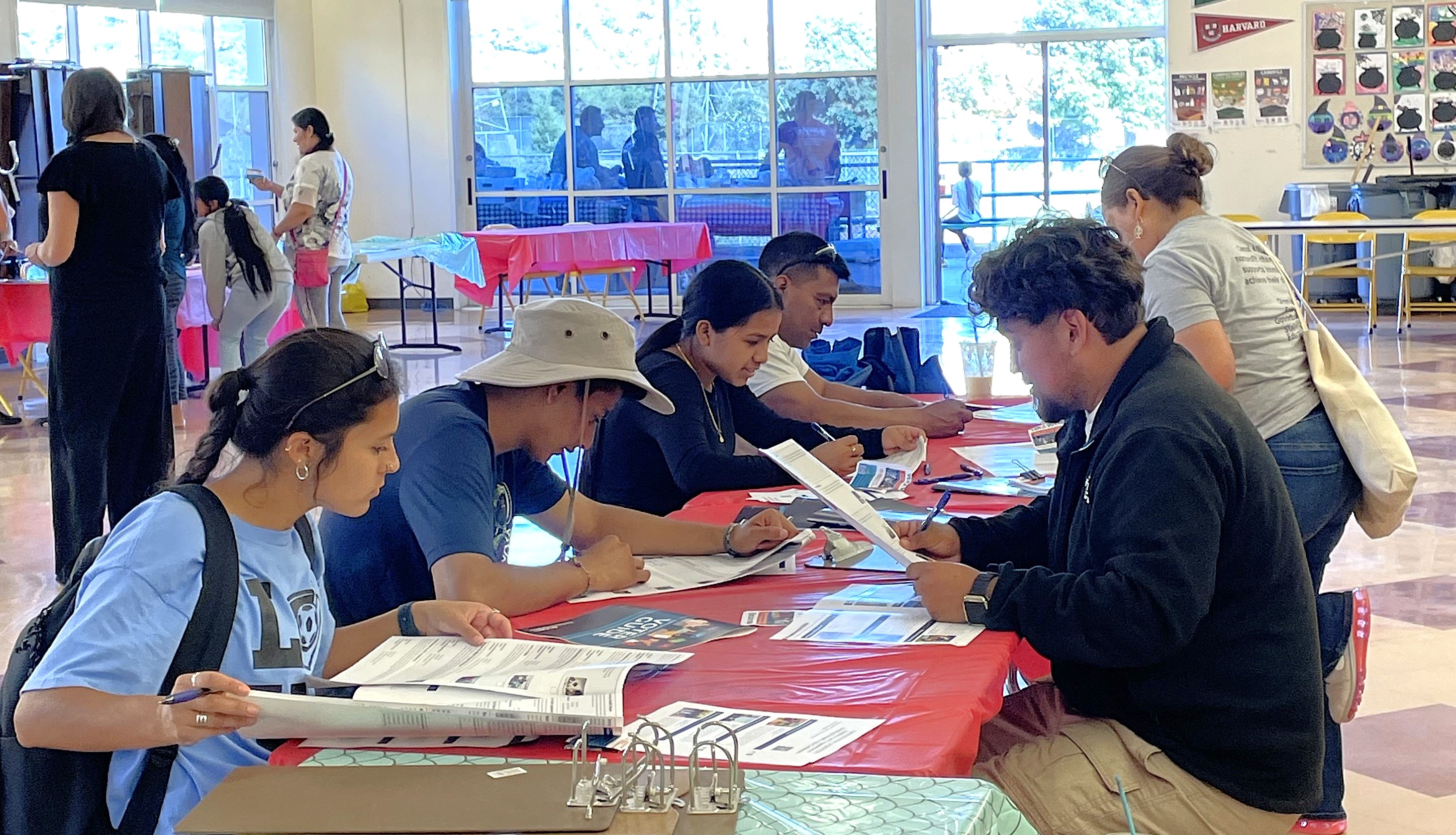 Several people sit at a table and look at materials as they consider voting for Participatory Budgeting projects.