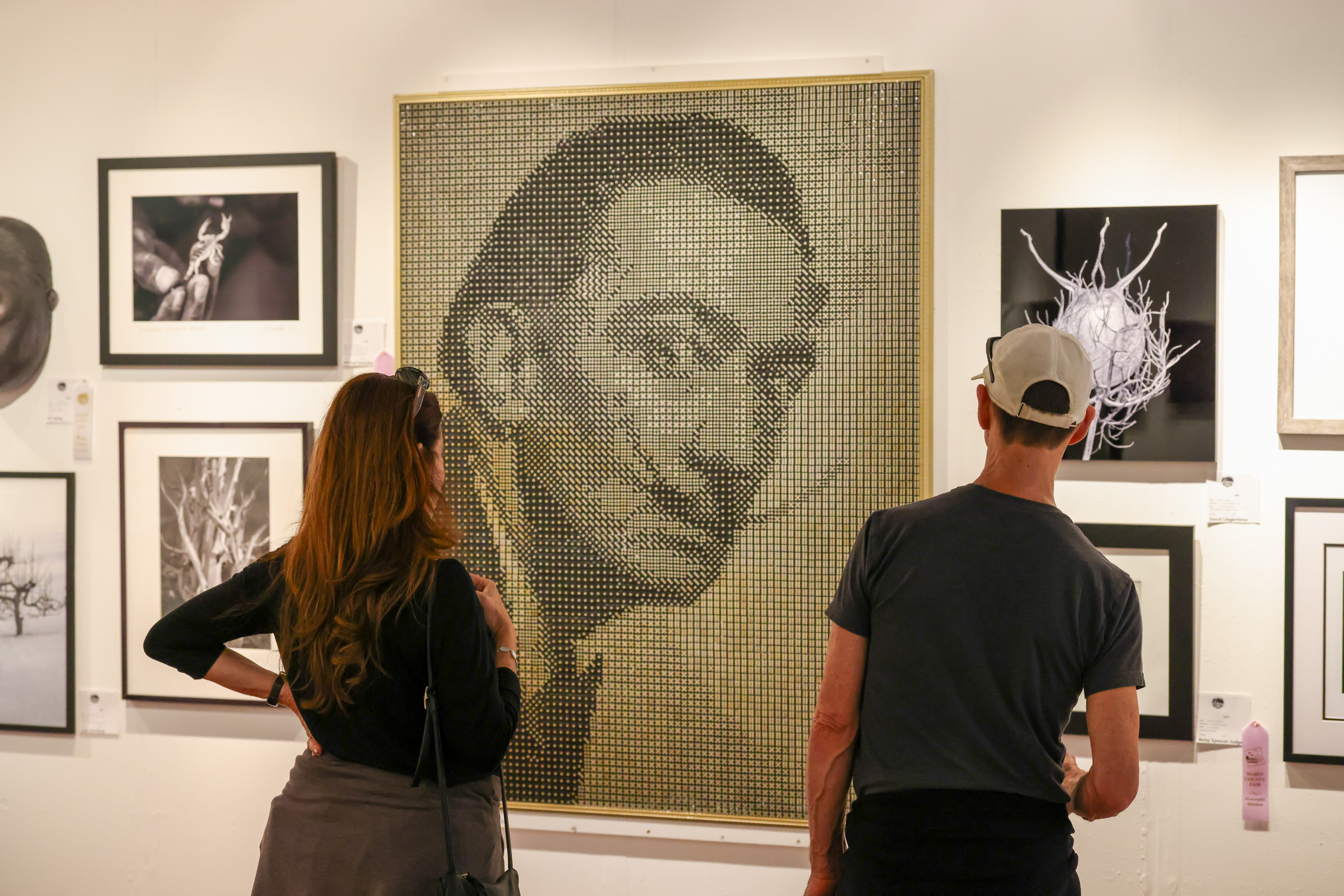Two people stand with their backs to the camera as they look at a large portrait of famed artist Salvador Dali.