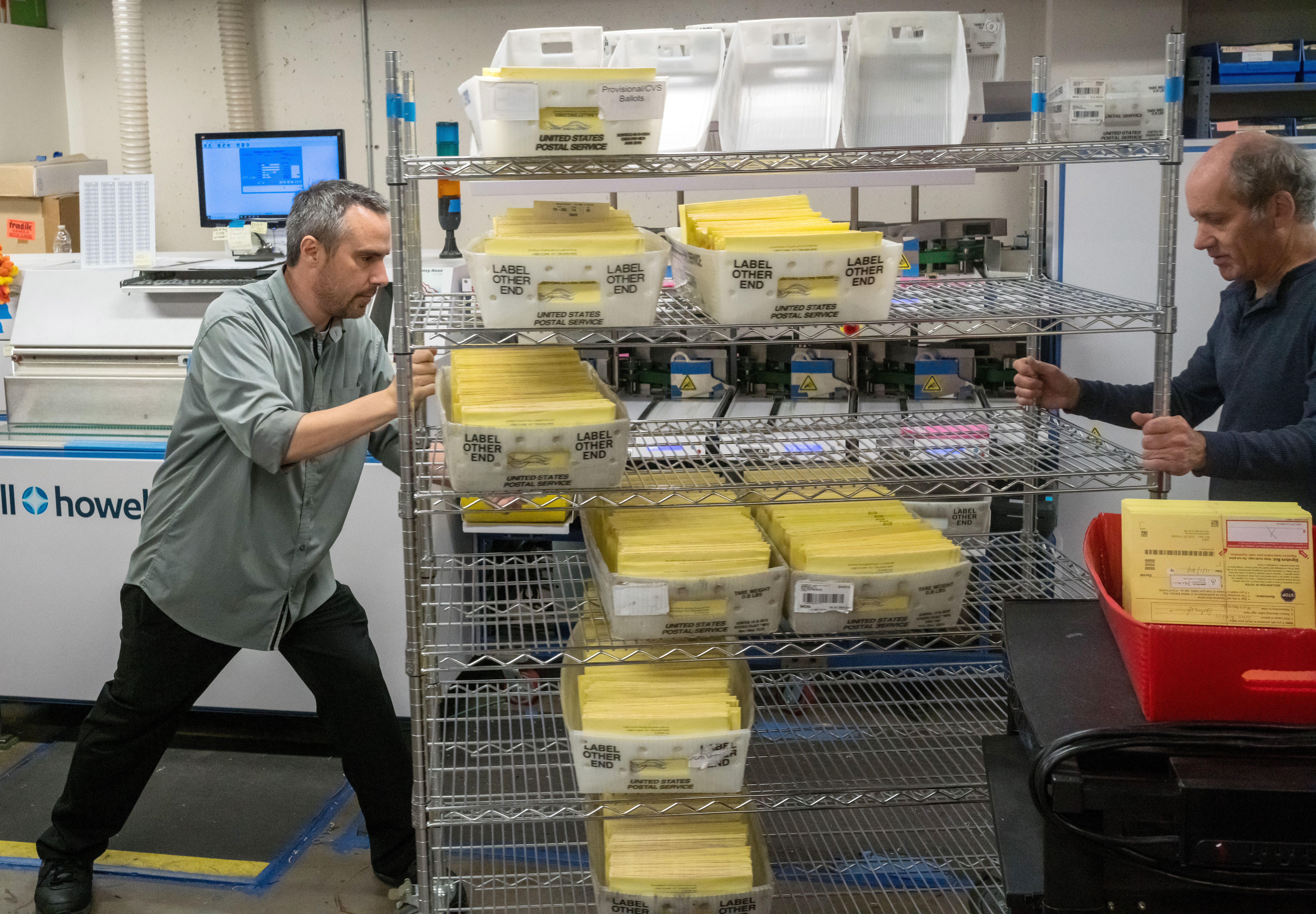 Two men push a cart with election envelopes