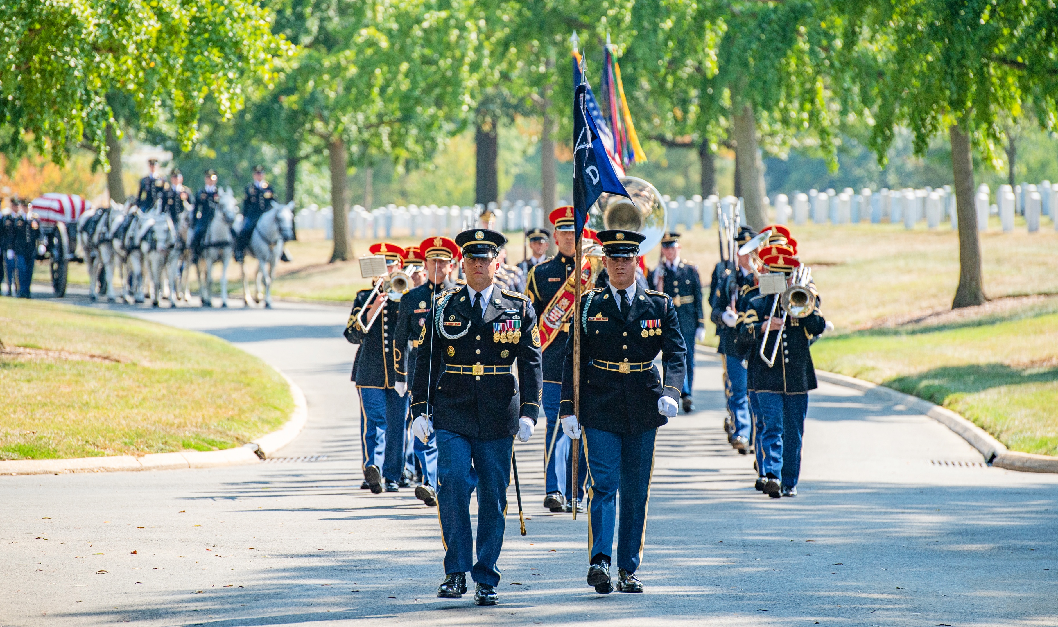 John Melolick holds a sword and marches in formal Army uniform with other soldiers in a burial procession.