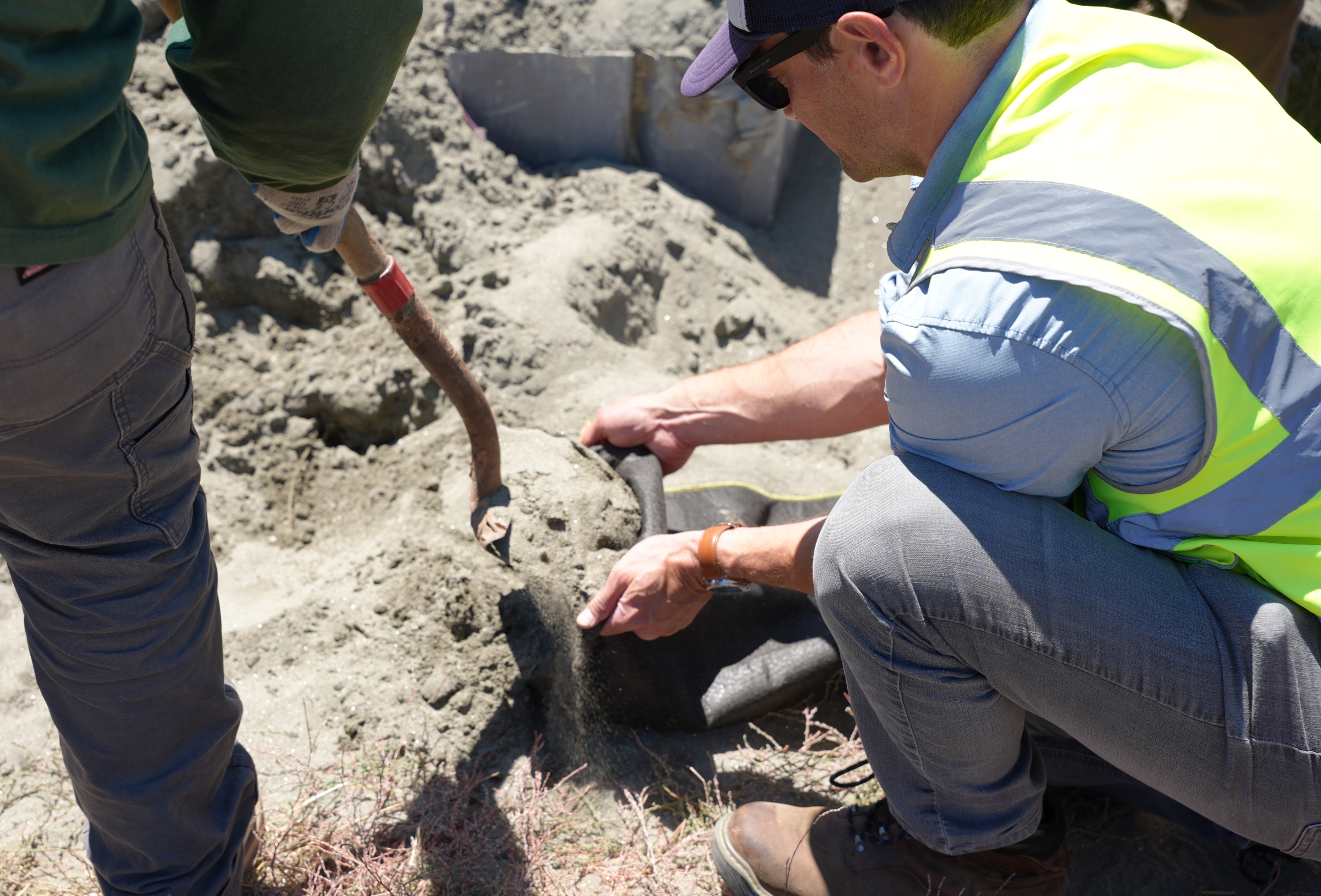 A man crouches down to make a sandbag.